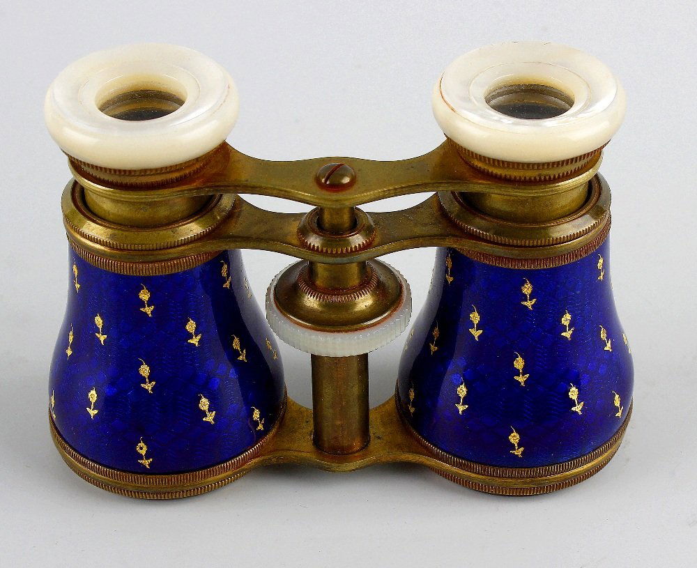 A pair of French enamel and mother of pearl mounted ope: A pair of French enamel and mother of pearl mounted opera glasses, the blue guilloche enamel barrels having gilt flower head decoration, upon a brass frame leading to the mother of pearl eyepieces, 2.