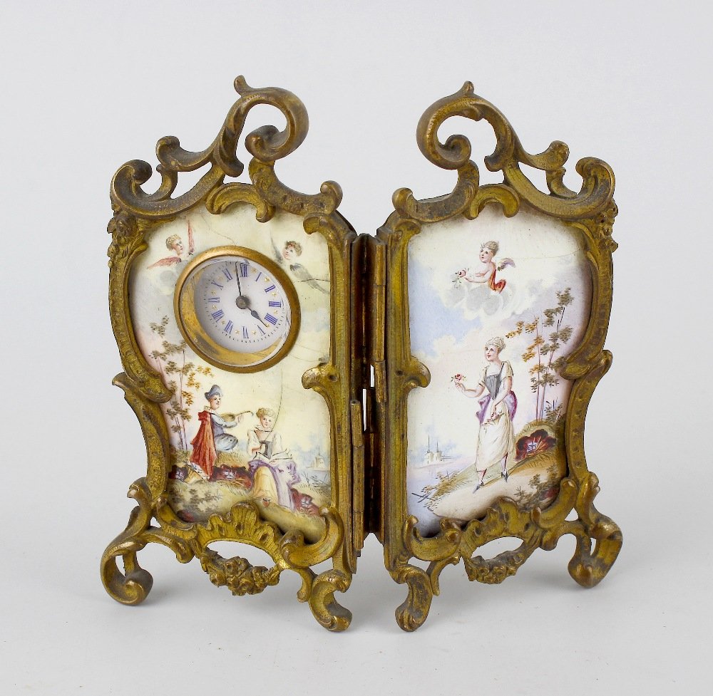 A 19th century brass and enamel desk timepiece.: A 19th century brass and enamel desk timepiece, the dual panels decorated with scene of figures and cherubs separated by a river, the left panel housing white enamel dial having Roman numerals, all wi