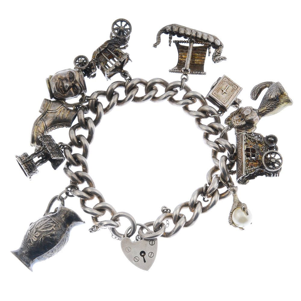 Two charm bracelets.: Two charm bracelets. The two heavy curb-link bracelets suspending a total of twenty-two charms to include a bird claw holding an imitation pearl together with a wishing well. Hallmark for London, 1972