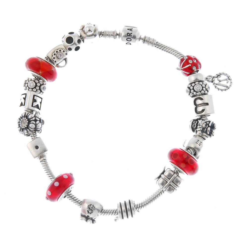 PANDORA - a charm bracelet.: PANDORA - a charm bracelet. The snake-link chain, suspending nineteen charms, to include a monkey, a present and a pig. One non designer charm. With maker's marks for Pandora. Length 23cms. Weight 73.