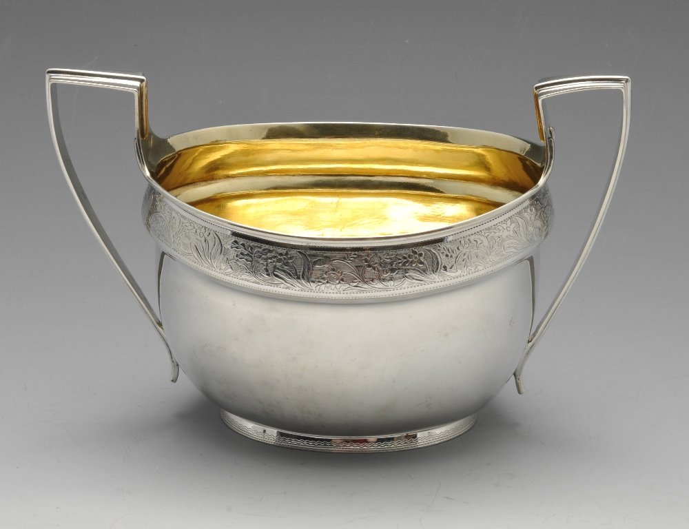 A 1930's silver sugar bowl.: A 1930's silver sugar bowl, the oval body with silver-gilt interior, floral engraved border and angular handles. Hallmarked William Comyns & Sons Ltd (Richard Comyns), London 1936. Height including ha
