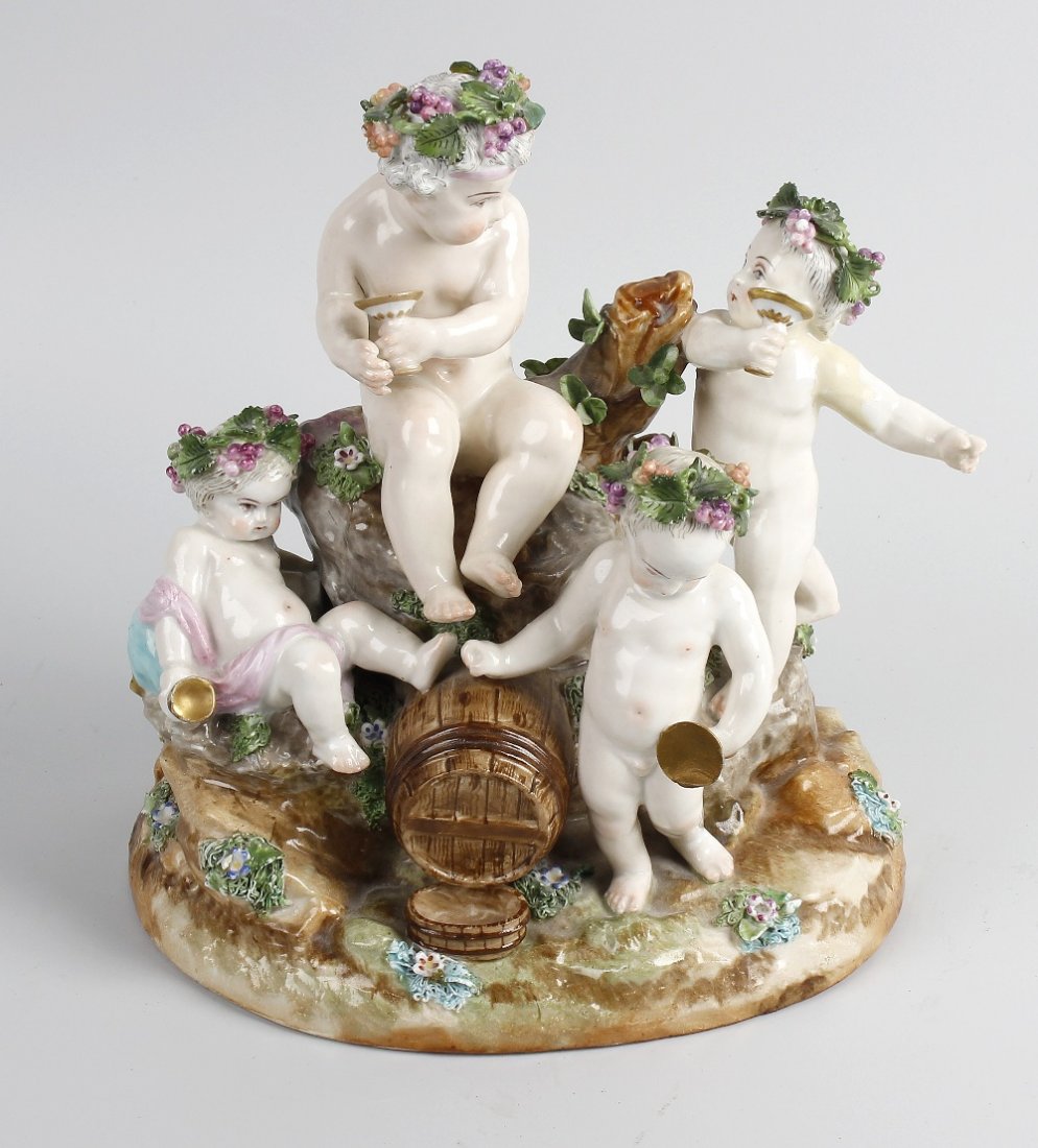 A German porcelain figure group.: A German porcelain figure group. Modelled as four Bacchus children seated upon a rock and wine barrel, crossed swords marks beneath, in the manner of Meissen, 9" (23 cm) high.