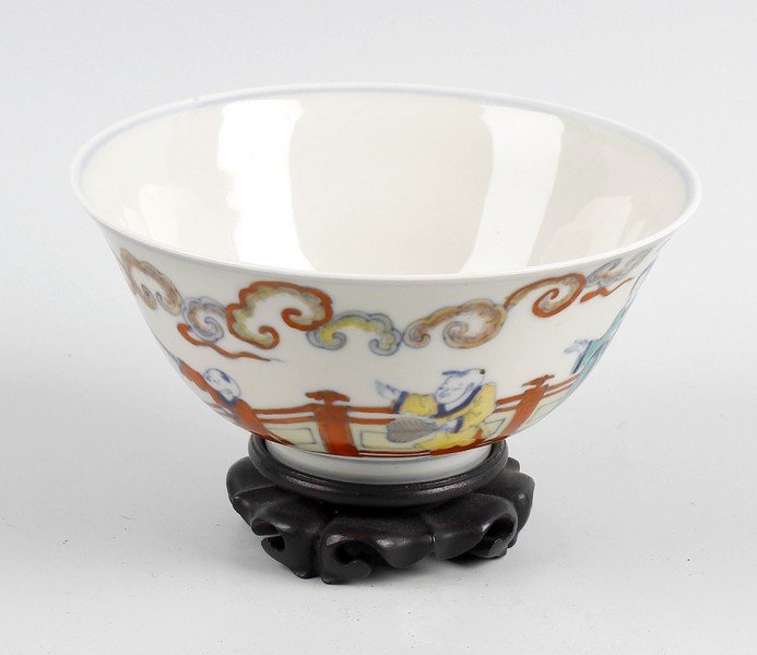 A 19th century Chinese porcelain bowl.: A 19th century Chinese porcelain bowl, with flared collar and footed base, white glazed and decorated with figures, painted blue six character mark to underside of base, upon carved wooden stand, 6" (