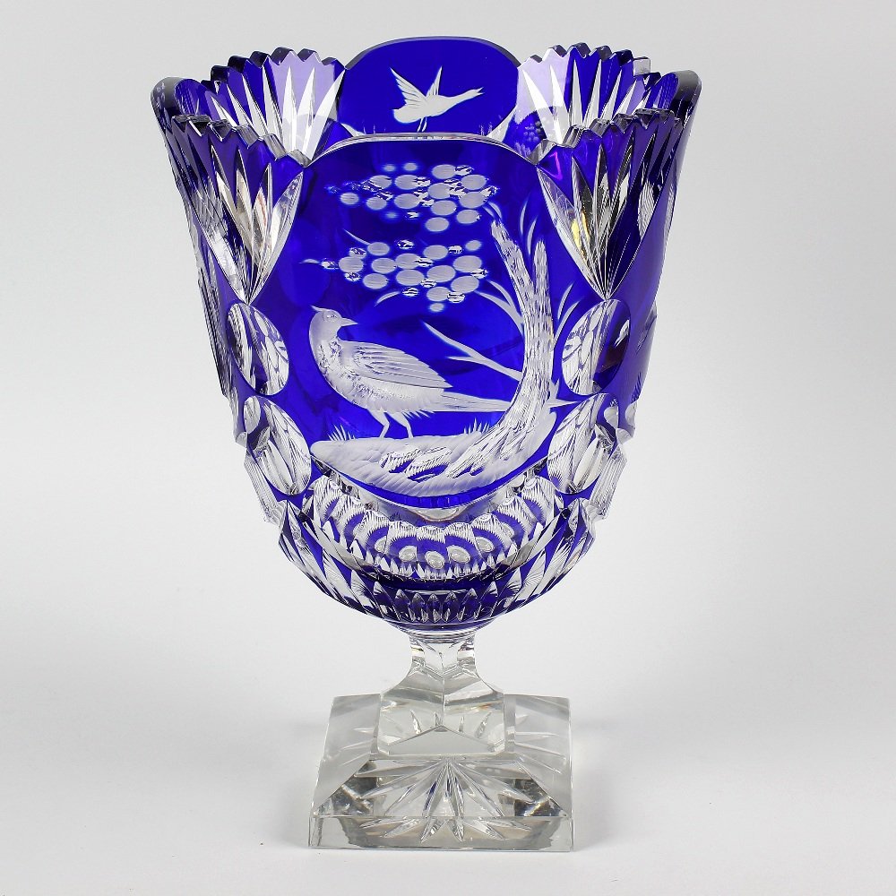 A heavy cut glass vase with frilled collage and bird: A heavy cut glass vase, the flash cut, blue overlaid glass bowl with frilled collar and bird decoration, upon a clear glass pedestal base, 11" (28cm) high.