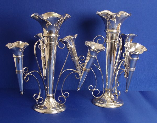 Walker & Hall - a pair of flower Epergnes the fil: Walker & Hall - a pair of flower Epergnes the filled circular bases rising to the central tapered vase with flared lip the scroll shaped frame with three radiating arms also supporting smaller identic