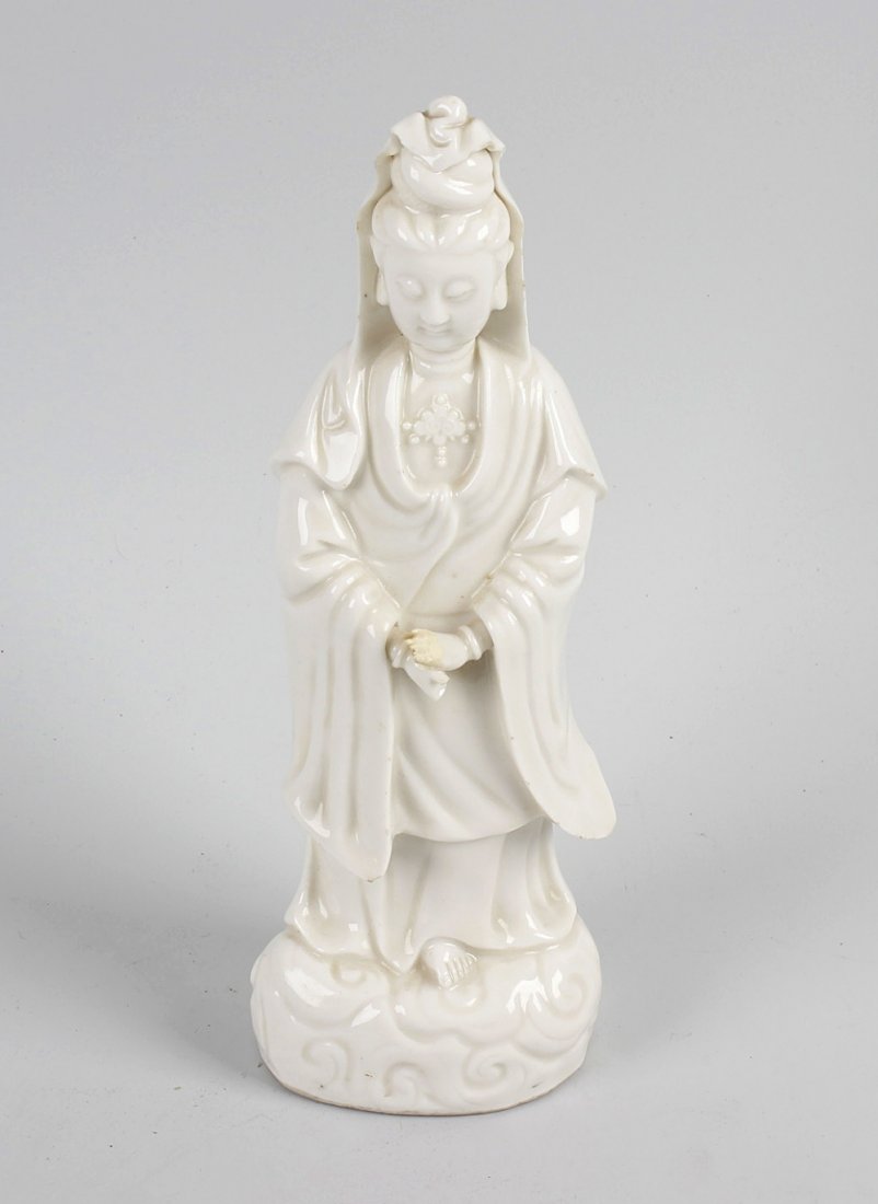 A 19th century Chinese blanc de chine figure, modelled: A 19th century Chinese blanc de chine figure, modelled as Guanyin stood in flowing robes upon a wave or cloud domed base, 10.75 (27.5cm). (a/f).