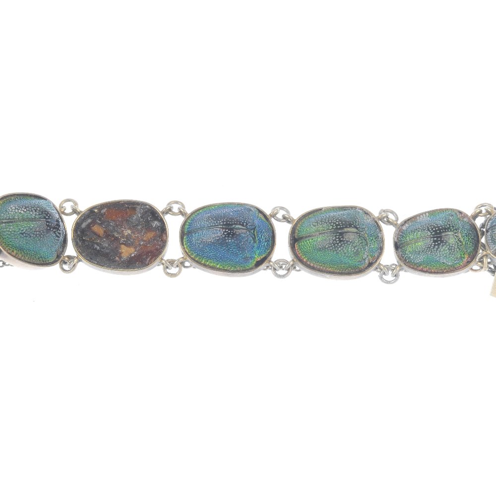 A scarab bracelet and brooch. The bracelet designed as: A scarab bracelet and brooch. The bracelet designed as graduated collet-set scarab beetle links to the push-piece clasp, extension and safety chain, together with a double scarab bar brooch. One beetl