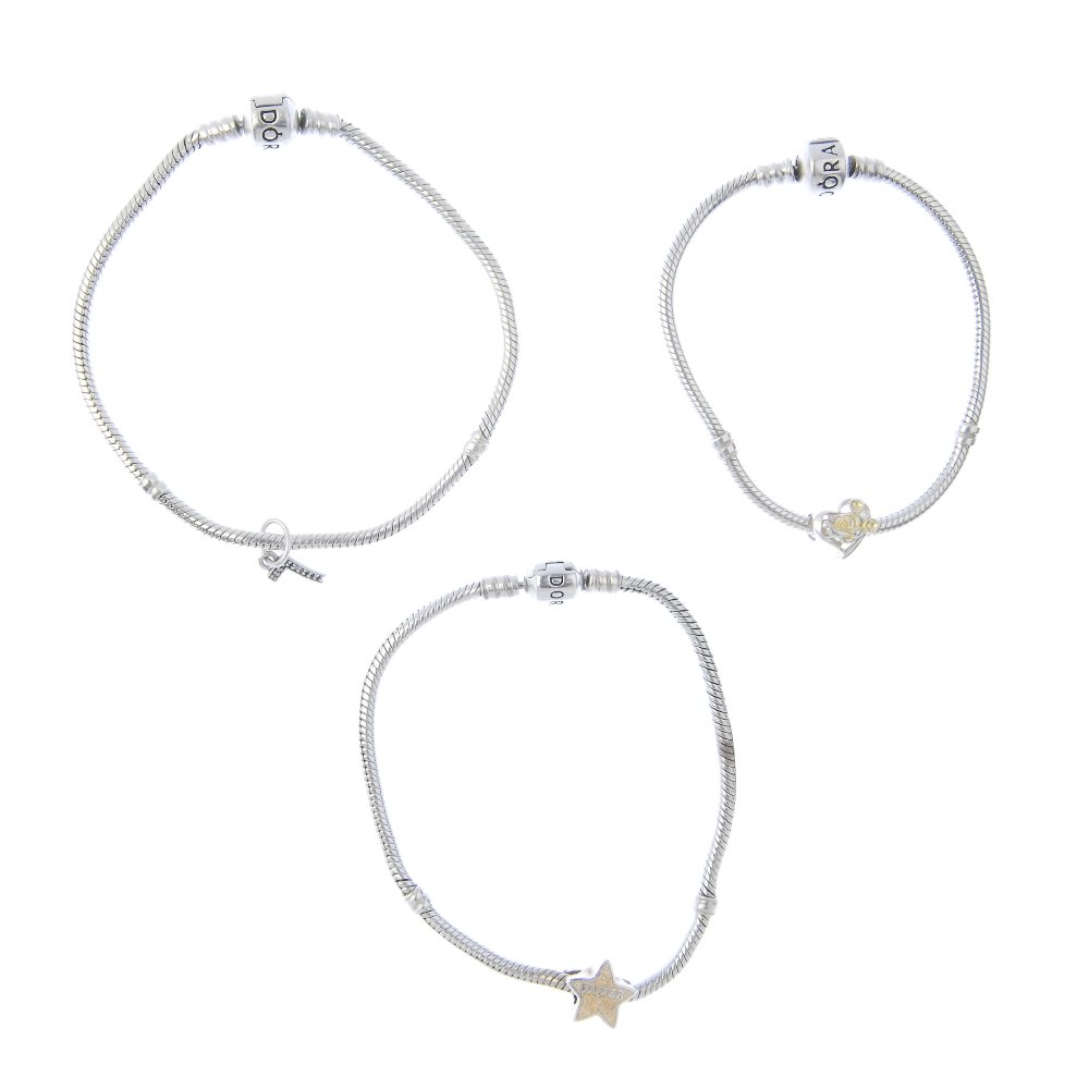 PANDORA - three charm bracelets. Suspending two non: PANDORA - three charm bracelets. Suspending two non designer charms and a cubic zirconia set Pandora initial charm, AF. With maker's marks. With marks to indicate silver. Lengths 17 to 20cms. Weight 4
