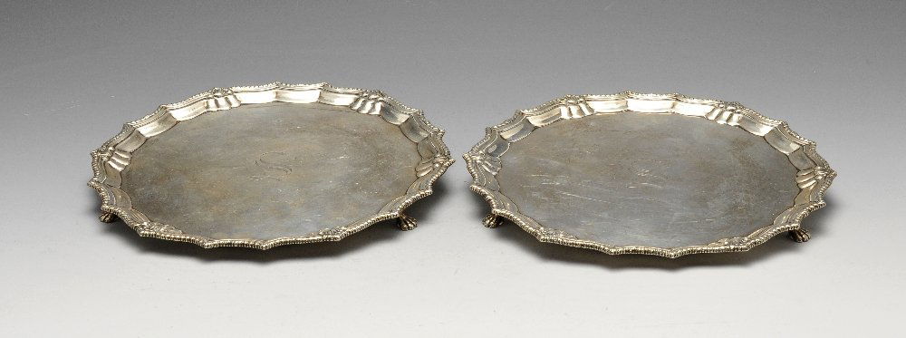 A pair of 1930's silver salvers, each having a: A pair of 1930's silver salvers, each having a scalloped and gadrooned rim with engraved initial to the centre and raised upon three paw feet. Hallmarked Barker Brothers Silver Ltd., Birmingham 1933.