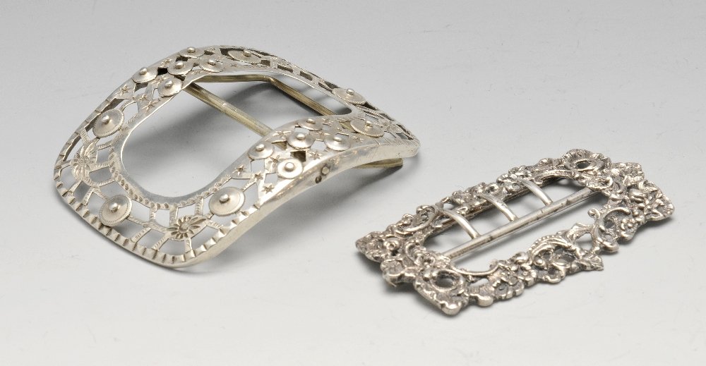 A late Victorian silver shoe buckle, cast and: A late Victorian silver shoe buckle, cast and embellished with floral scrolls, hallmarked Chester 1897, length measuring 8 cm. Together with a Dutch silver shoe buckle, silver rattles and two novelty