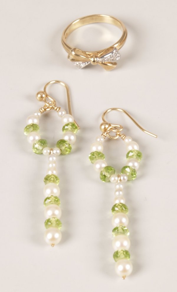 Two items of jewellery to include a 9ct gold pave: Two items of jewellery to include a 9ct gold pave diamond set bow ring and a pair of peridot and cultured pearl dropper earrings in a circular design leading to a bar drop with alternating peridots an