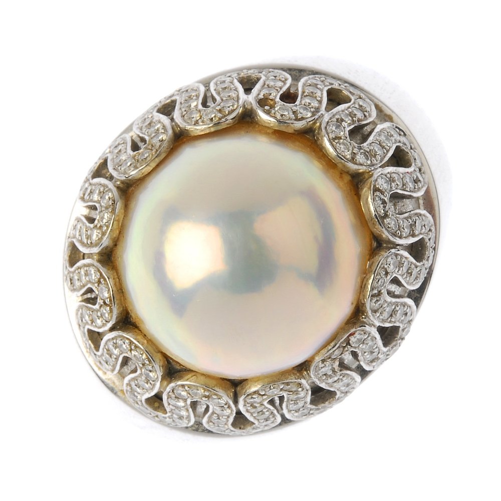 VERSACE - a mabe pearl and diamond ring. The mabe: VERSACE - a mabe pearl and diamond ring. The mabe pearl, with brilliant-cut diamond scrolling surround and tapered band. One diamond deficient. Stamped Gianni Versace. Estimated total diamond weight 1