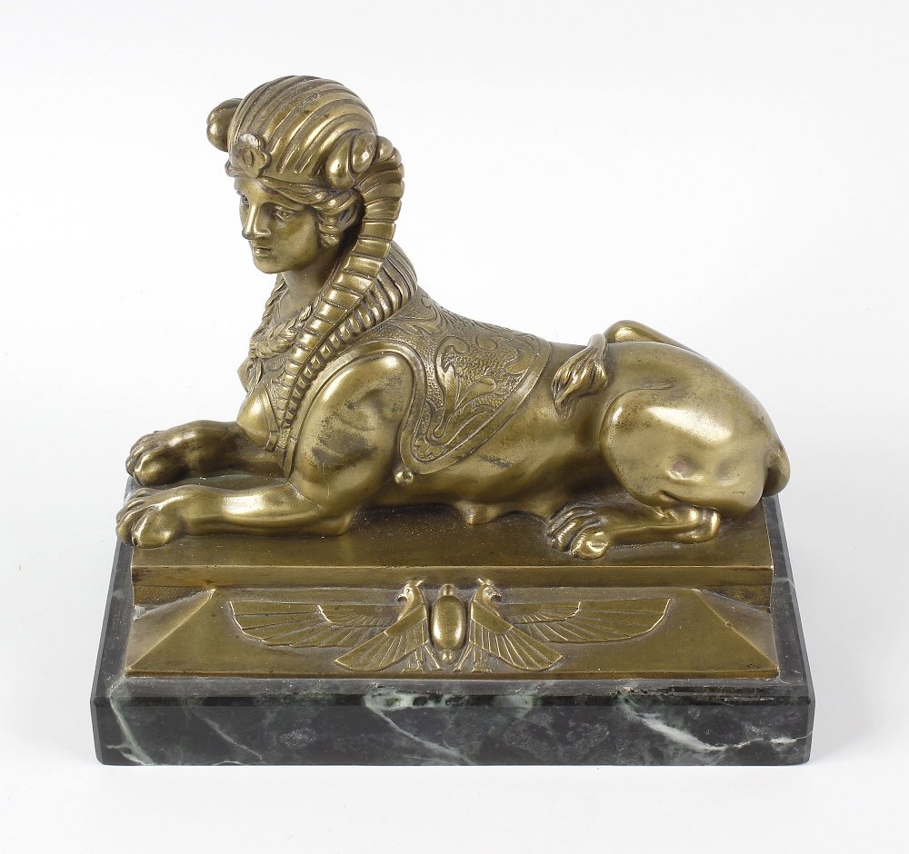 A 19th century gilt bronze figure, modelled as a sphinx: A 19th century gilt bronze figure, modelled as a sphinx laid upon a rectangular base having scarab and falcon frieze, and further green marble base, 8.25 (21cm) long. With heavy rubbing and wear causi