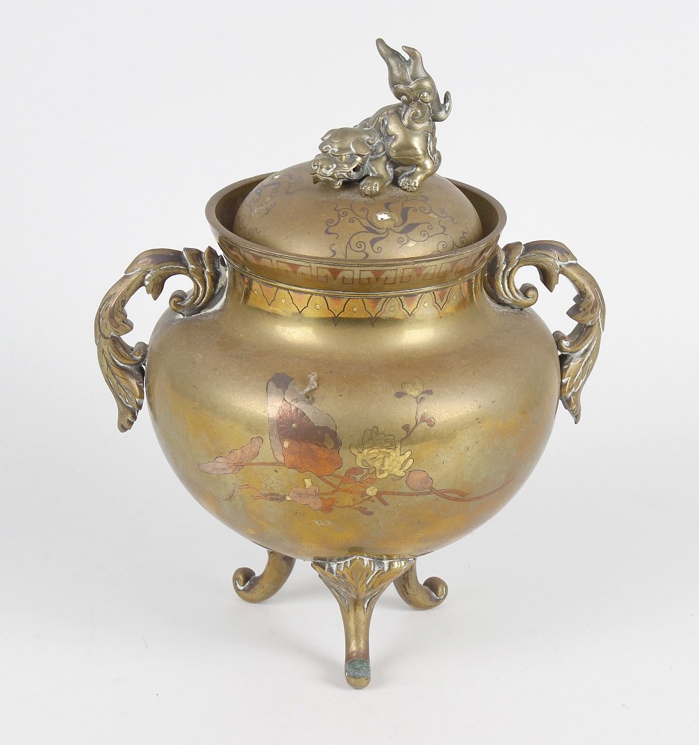 An inlaid bronze incense burner or koro, of squat form: An inlaid bronze incense burner or koro, of squat form decorated with bi-tone inlaid floral sprays, having twin foliate handles leading to the short flared neck and pierced cover having shishi finial,