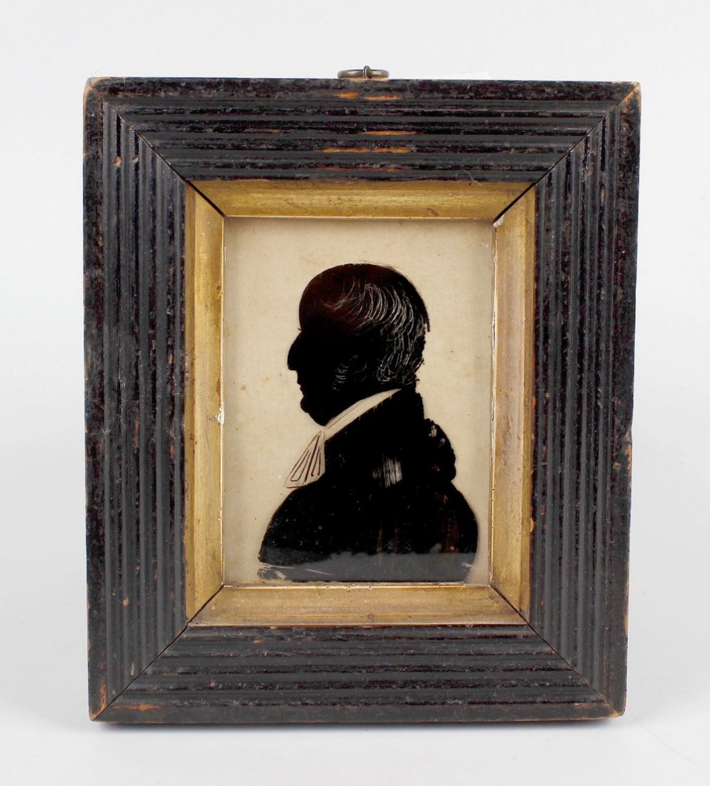 A silhouette on glass, depicting Reverend Samuel Cory: A silhouette on glass, depicting Reverend Samuel Cory with detailed paper label verso, 2.5 x 3.5 (6.5 cm x 9 cm), in wooden frame. Overall in fair to poor condition with dirt and scratches to glass. F