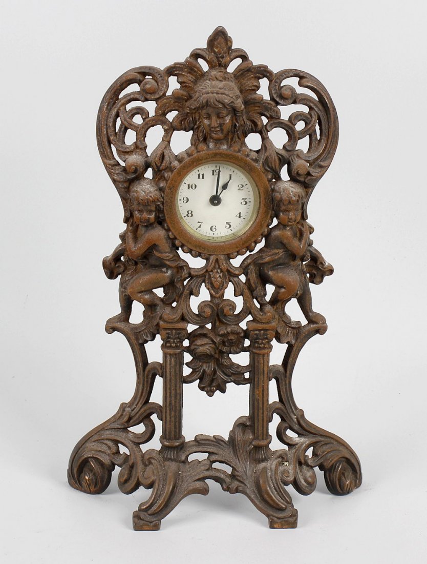 A small late 19th century timepiece within a gilt metal: A small late 19th century timepiece within a gilt metal drum shaped case and large cast metal outer frame of pierced scrolled form decorated with cherubs, a similar wall hanging, combined clock and ba