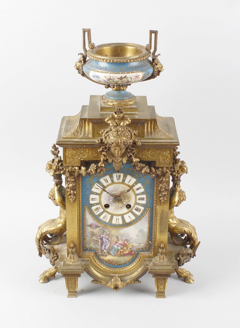 A 19th century French ormolu and porcelain clock: A 19th century French ormolu and porcelain clock garniture. Japy Freres & Cie, Paris, circa 1860, the clock having a cellular Roman dial with painted central quiver of arrows above a scene of figures 