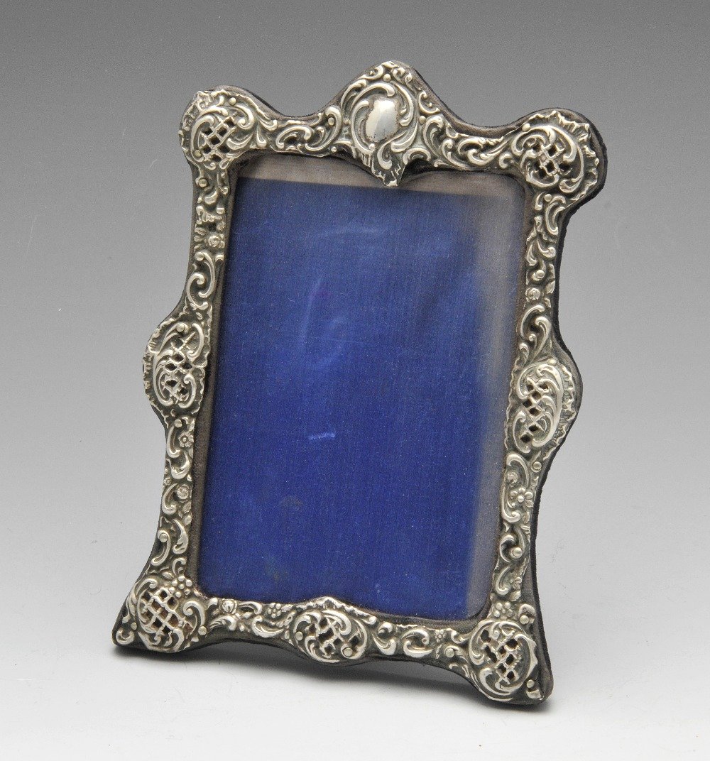 An Edwardian silver mounted photograph frame, decorated: An Edwardian silver mounted photograph frame, decorated with lozenge and scroll piercing with a vacant cartouche. Hallmarked Henry Matthews, Birmingham 1901. Height measures 7 4/8 inches (19 cm). The