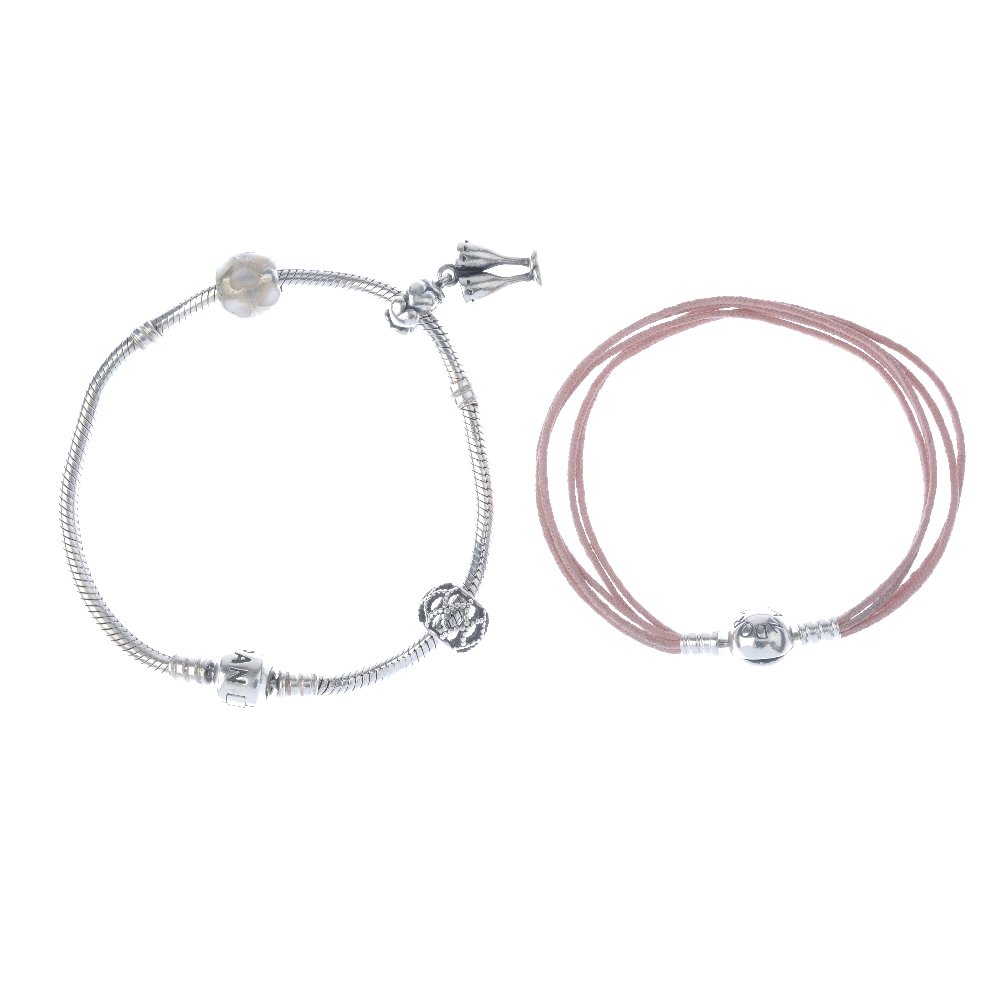 PANDORA - three charm bracelets. To include two charm: PANDORA - three charm bracelets. To include two charm bracelets and a pink cord bracelet, suspending a total of six Pandora and one non-designer charms, to include a heart-shape charm with pink paste