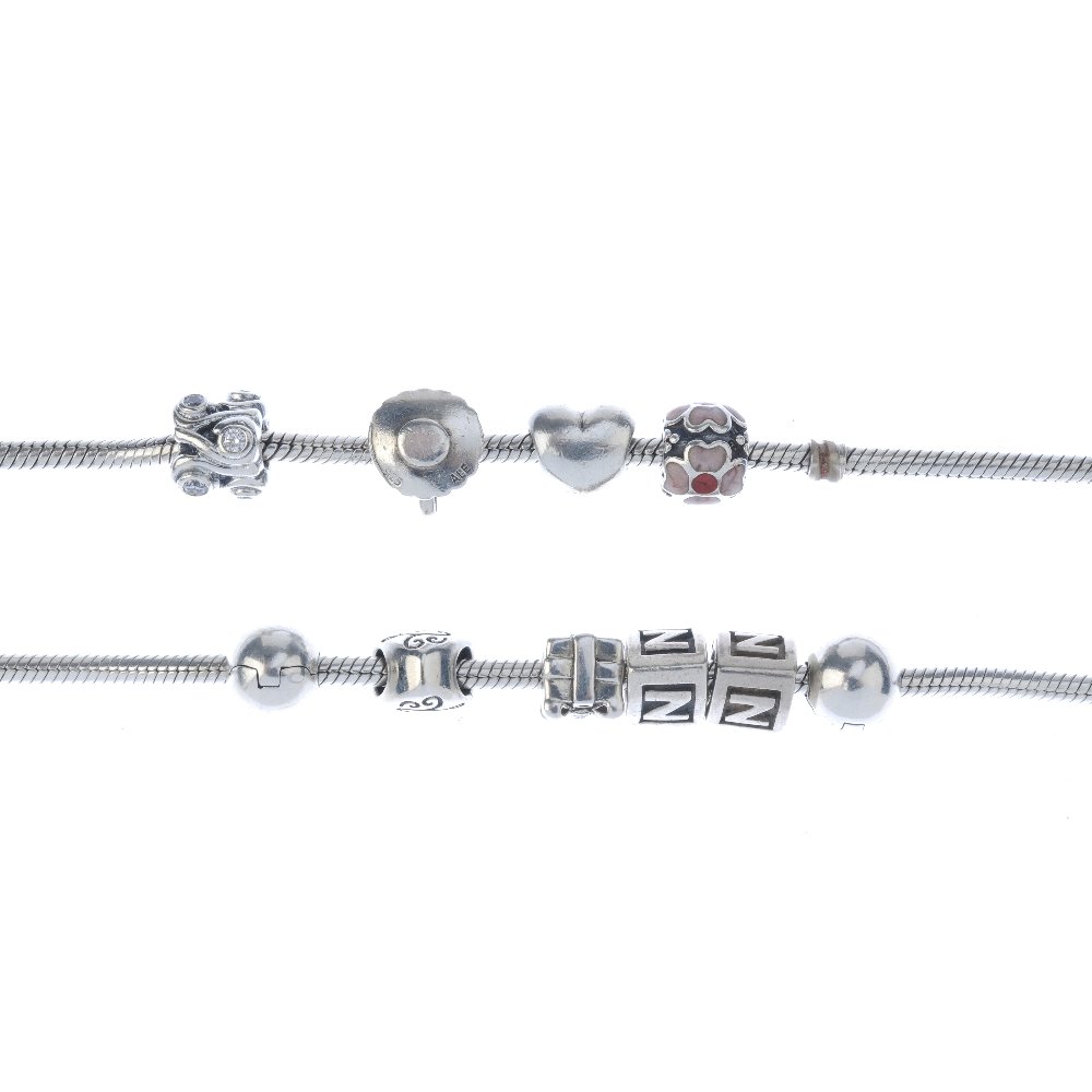 PANDORA - two charm bracelets. Suspending a total of: PANDORA - two charm bracelets. Suspending a total of eight Pandora charms to include a cup and saucer and a heart and two non designer charms. With maker's marks. Lengths 19.5cms. Weight 59gms.