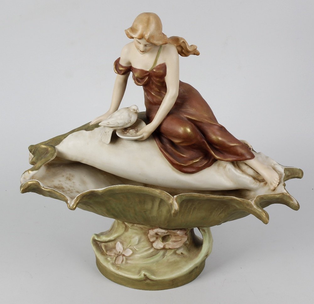 A Royal Dux centrepiece, modelled as a young girl: A Royal Dux centrepiece, modelled as a young girl seated upon the edge of a shell (forming the bowl), feeding a single dove, the underside of the naturalistic modelled base with applied pink dux trian