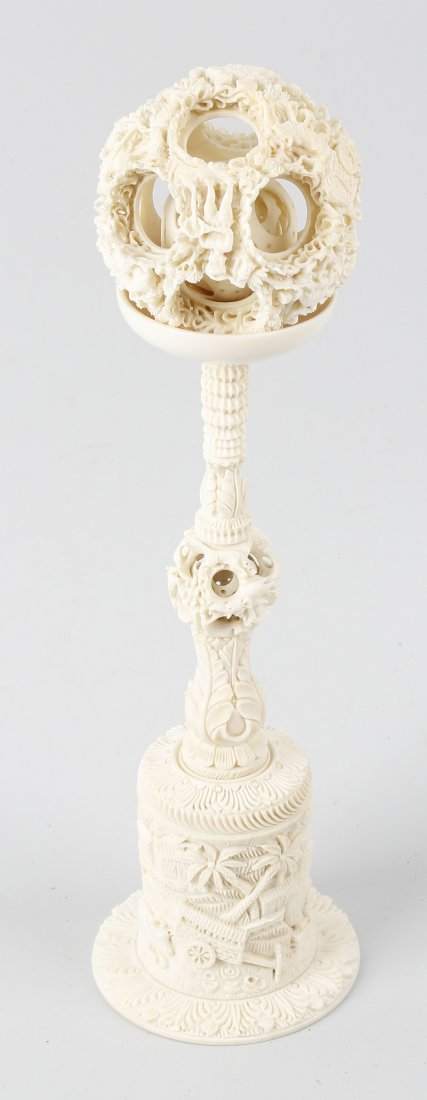 A Canton ivory puzzle ball, comprised of approximately: A Canton ivory puzzle ball, comprised of approximately eight pierced concentric layers, the outer layer carved with Eastern figures at work, the ball raised upon a highly decorative stand with knopped