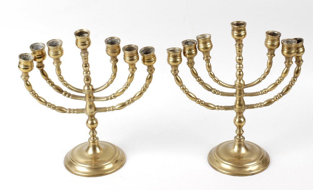 A pair of brass Menorah candlesticks, each having three: A pair of brass Menorah candlesticks, each having three knopped branches to the central stem leading to the spreading circular base, 10.5 (26.75cm). With distortion to branches and few small knocks th