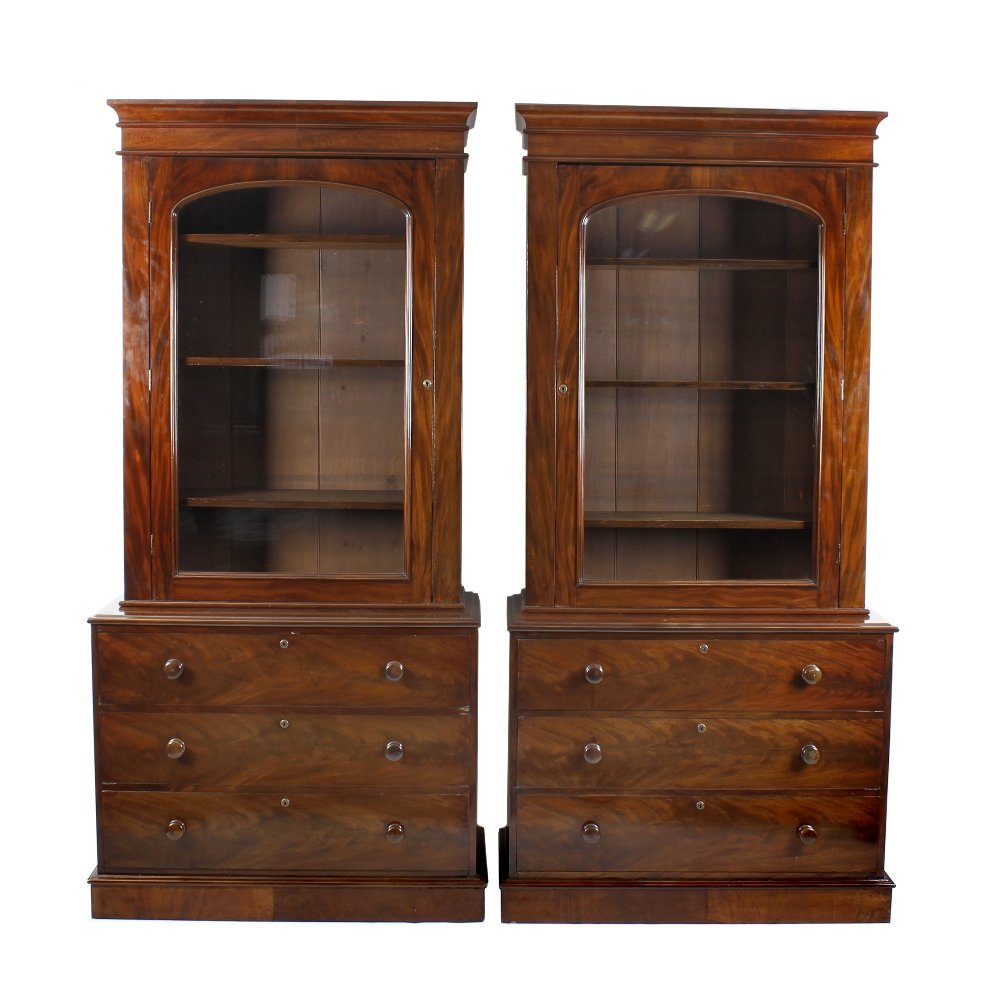 A near pair of late 19th century mahogany bookcases,: A near pair of late 19th century mahogany bookcases, each with an upper section having a projecting shaped cornice, above an arched glazed panelled door enclosing adjustable wooden shelves, the base w