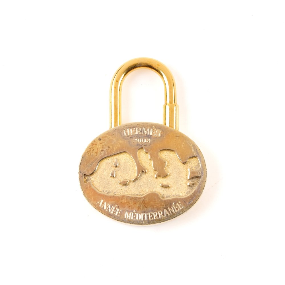 HERMES - an Anne Mditerrane lock charm. Designed: HERMES - an Anne Mditerrane lock charm. Designed with an oval shape in gold-tone hardware, with front engraved Anne Mditerrane motif and maker's logo, with screw top closure. Lock charm is in fair ove