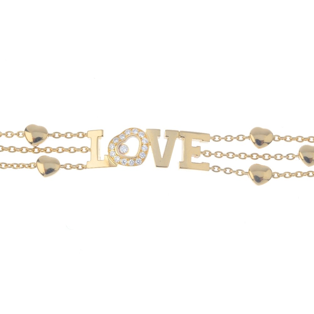 CHOPARD - an 18ct gold 'Happy Diamonds' bracelet. The: CHOPARD - an 18ct gold 'Happy Diamonds' bracelet. The 'love' script with brilliant-cut diamond free-moving collet glazed heart highlight, to the heart accent trace-link triple chain sides. Signed and