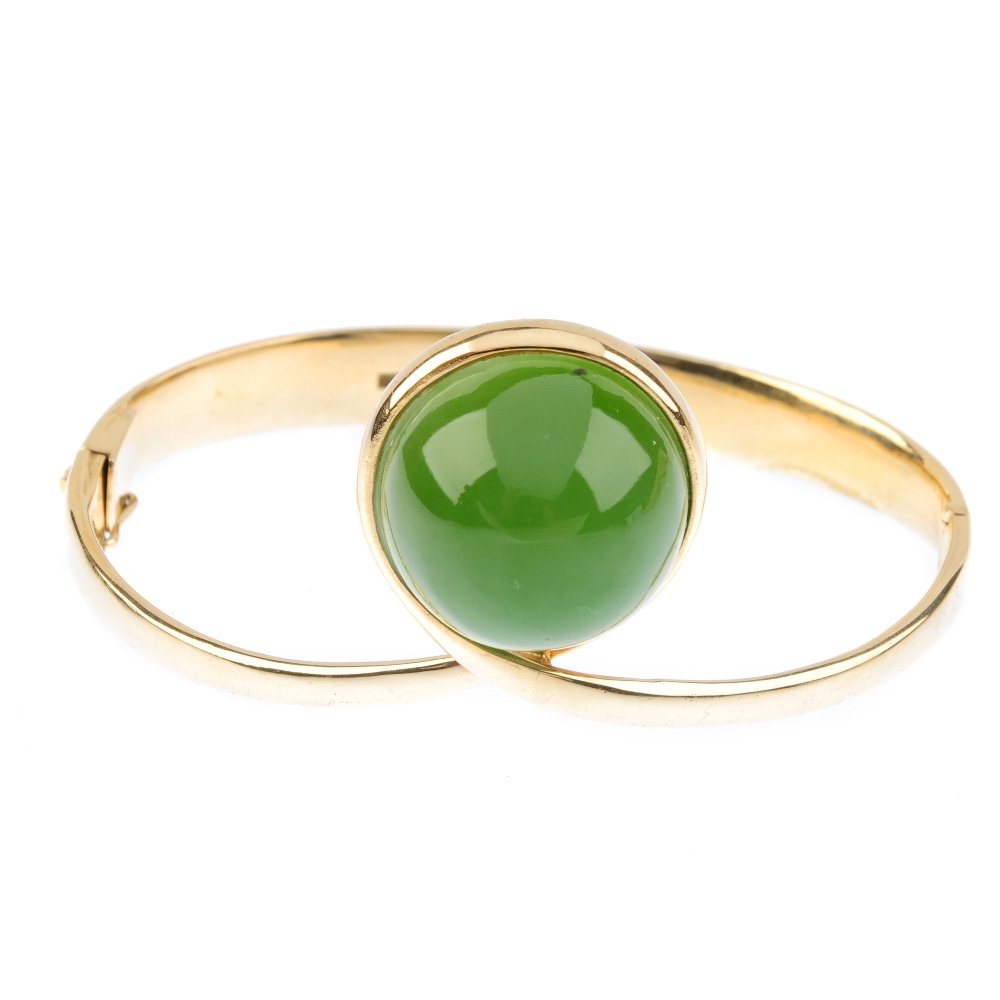 OLE LYNGGAARD - a 1970s Danish 14ct gold nephrite jade: OLE LYNGGAARD - a 1970s Danish 14ct gold nephrite jade hinged bangle. The circular nephrite jade cabochon, off-set in a crossover mount to the slightly tapered half-bangle. Maker's marks for Ole Lyngg