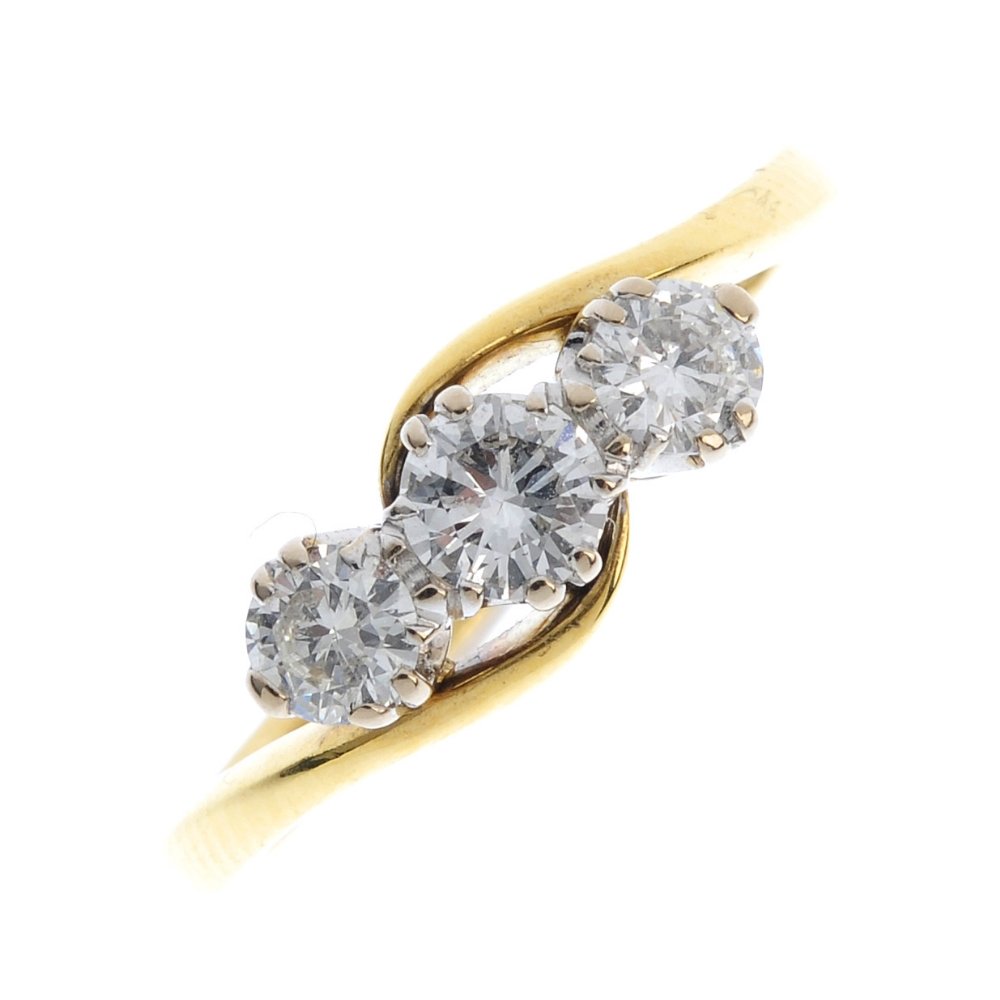 An 18ct gold diamond three-stone crossover ring. The (1 of 3)