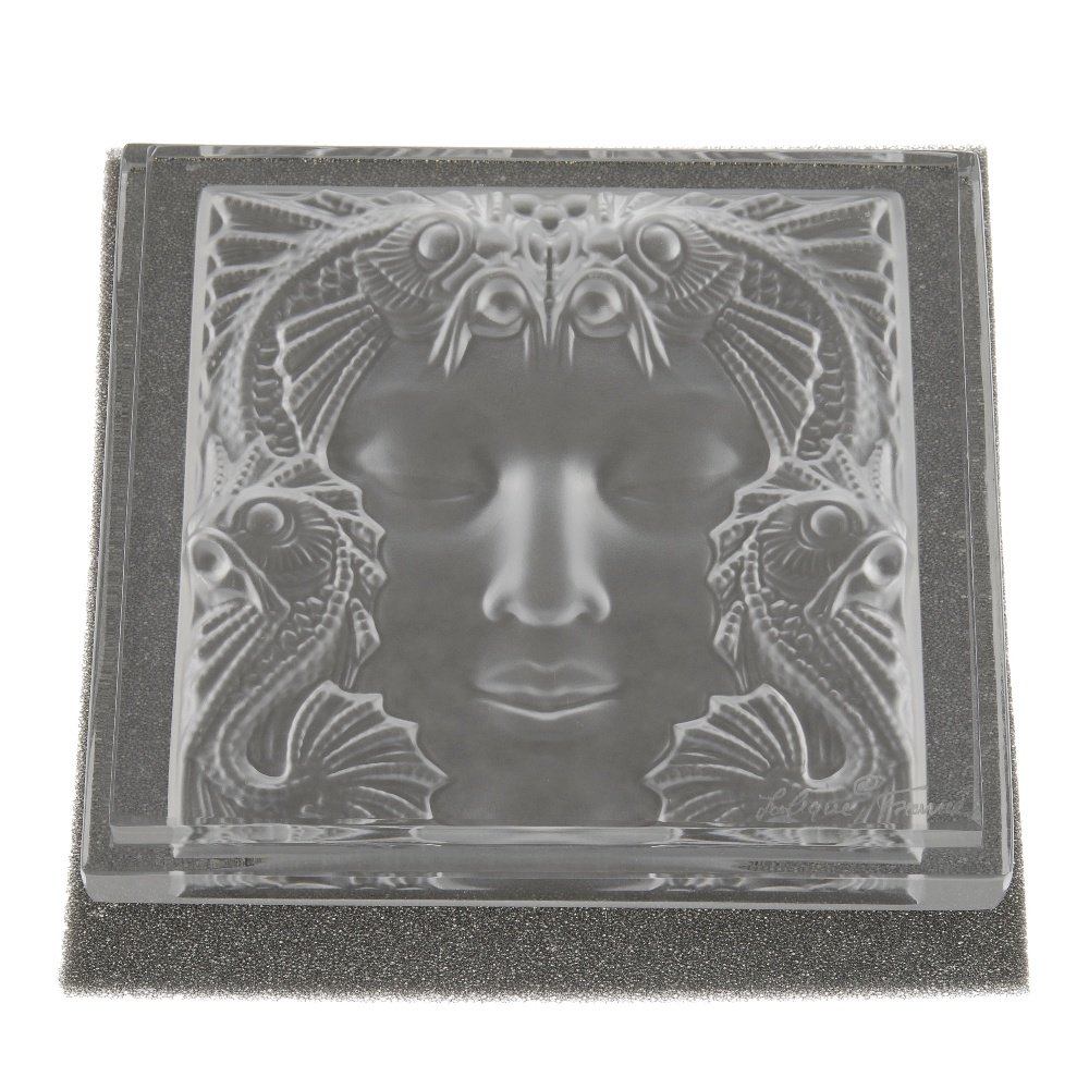 LALIQUE - an ornament. Designed as a glass square, the: LALIQUE - an ornament. Designed as a glass square, the reverse intaglio depicting a face with sea serpents around. Signed Lalique, France. Length 11.3cms. With maker's box and gift bag.