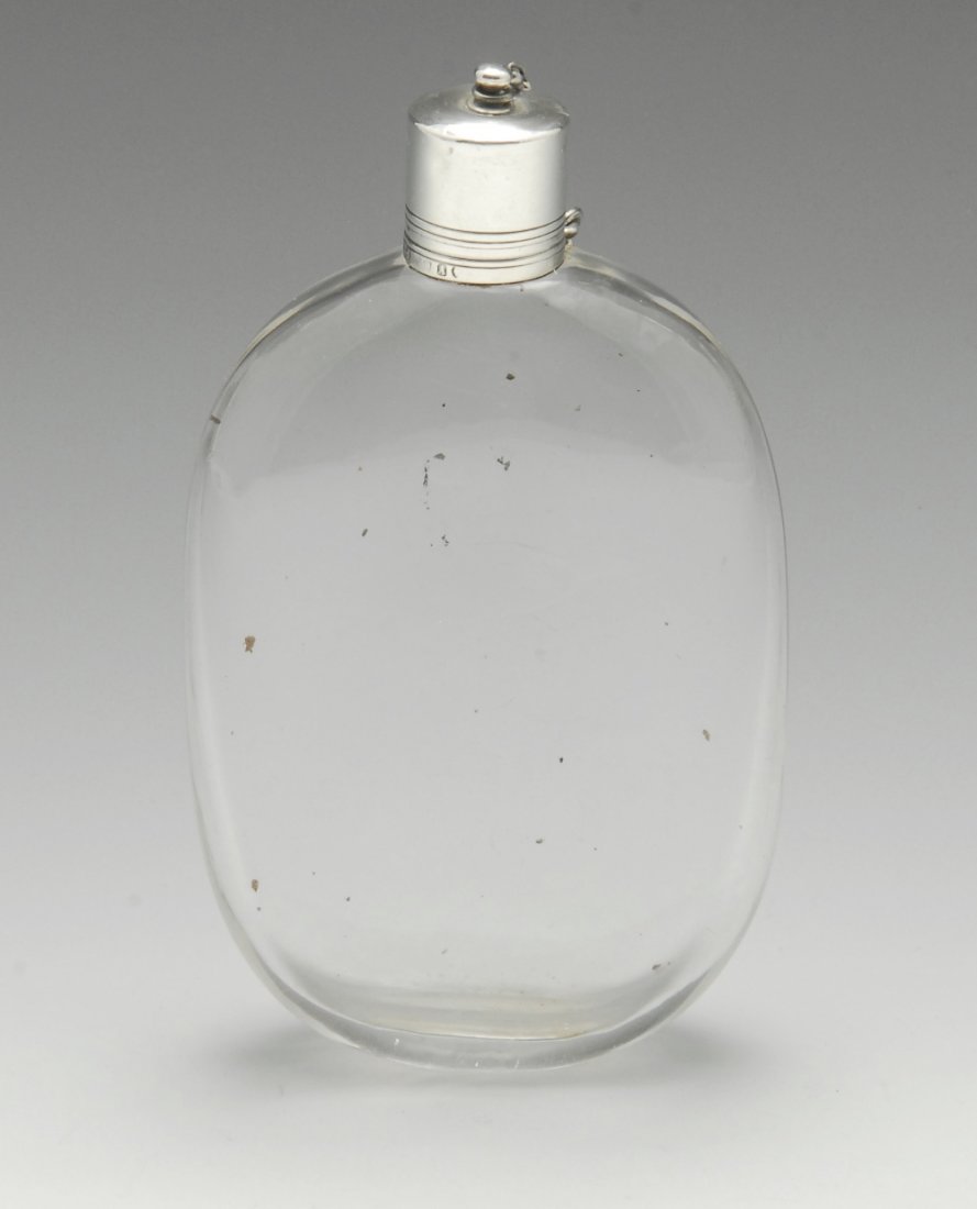 A Victorian silver mounted flask, the clear glass body: A Victorian silver mounted flask, the clear glass body with applied silver neck and cylindrical screw lid suspended on a chain. Hallmarked to neck only Thomas Johnson I, London 1876. Height measures 5