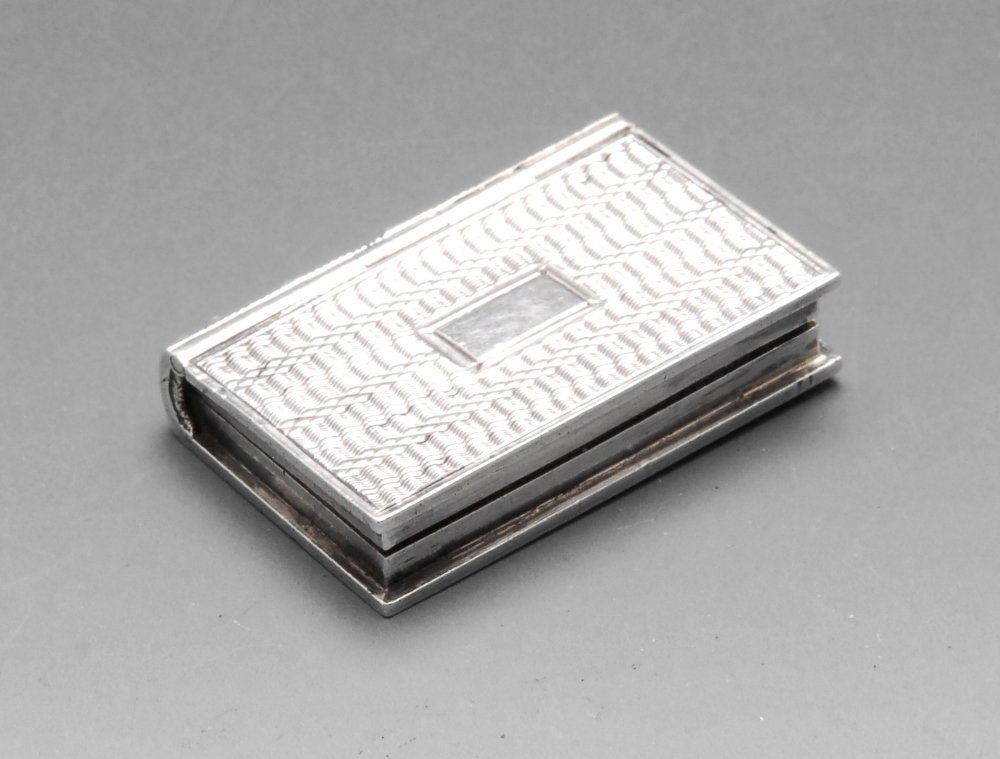 An early nineteenth century silver vinaigrette modelled: An early nineteenth century silver vinaigrette modelled as a book with engine-turned decoration and opening to a silver-gilt interior with pierced grille. Hallmarked Taylor & Perry (John Taylor & John