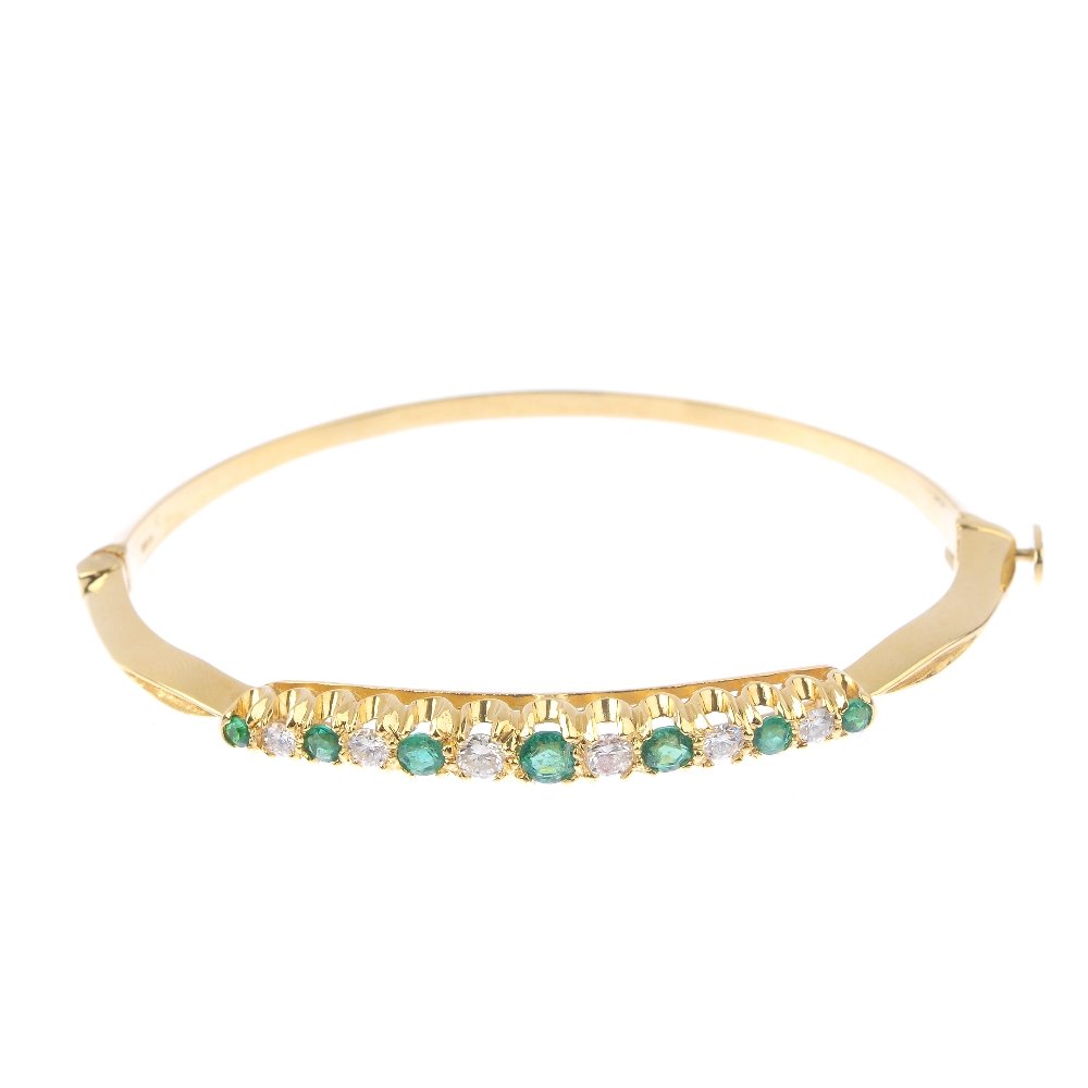 An 18ct gold emerald and diamond hinged bangle. (1 of 2)