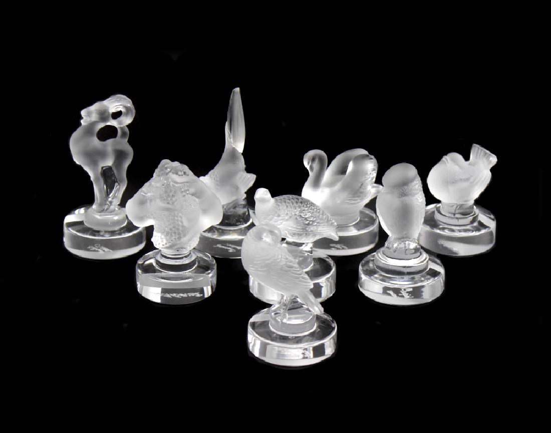 A group of eight Lalique glass menu or place card: A group of eight Lalique glass menu or place card holders. Each with slot to integral circular base, comprising: a swan, partridge, turtle dove, hawk, finch (s/d), pheasant (a/f), mountain goat, and '