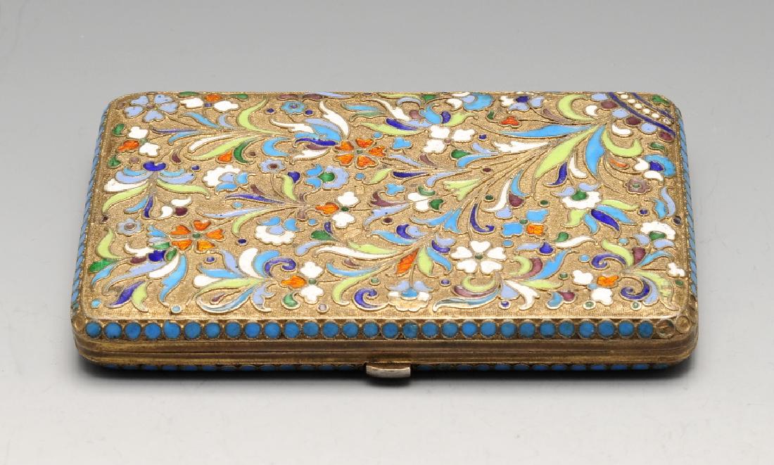 A turn of the century Russian silver-gilt and enamel: A turn of the century Russian silver-gilt and enamel cigarette case, the hinged oblong body with cloisonné enamel to both sides with floral motifs in shades of blue, green, orange and white upon a st
