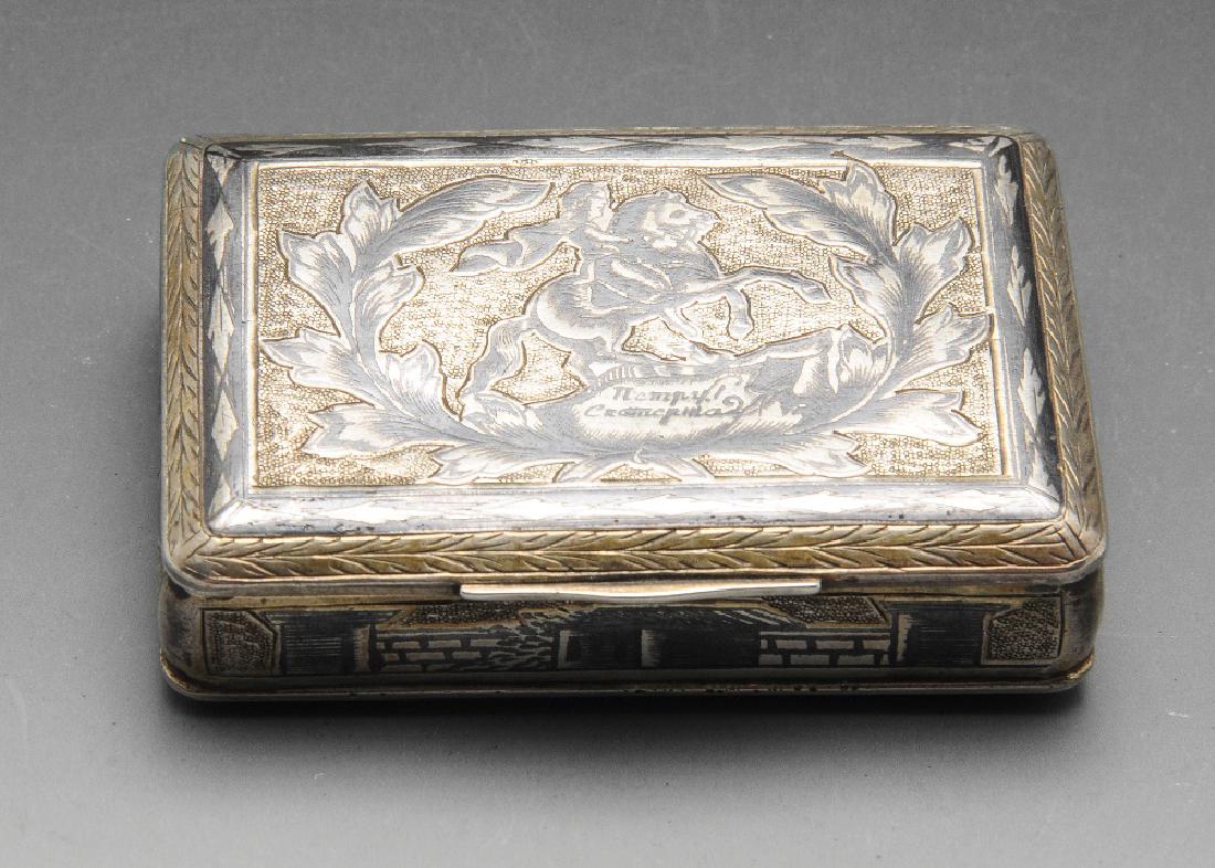 An early nineteenth century Russian silver-gilt and: An early nineteenth century Russian silver-gilt and Niello snuff box, of oblong hinged form, the cover depicting the Monument to Peter the Great within laurel wreath, the reverse with a similar wreath
