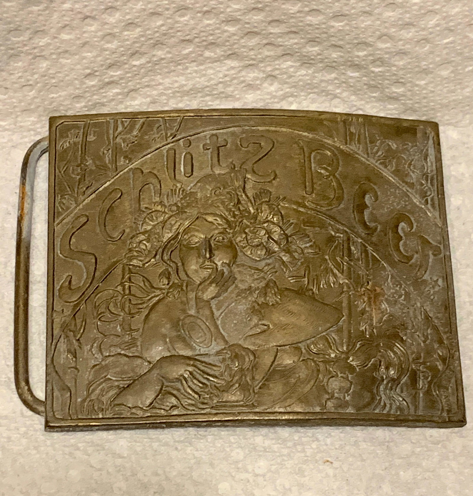 ANTIQUE SCHLITZ BEER EMBOSSED WOMAN BELT BUCKLE: ANTIQUE SCHLITZ BEER EMBOSSED WOMAN BELT BUCKLE. IN EXCELLENT SHAPE AND OVERALL CONDITION. HAS MAKER MARKS ON THE BACK WITH THE SERIAL NUMBER. A GREAT FIND AND AN EXCELLENT ADDITION TO YOUR COLLECTION