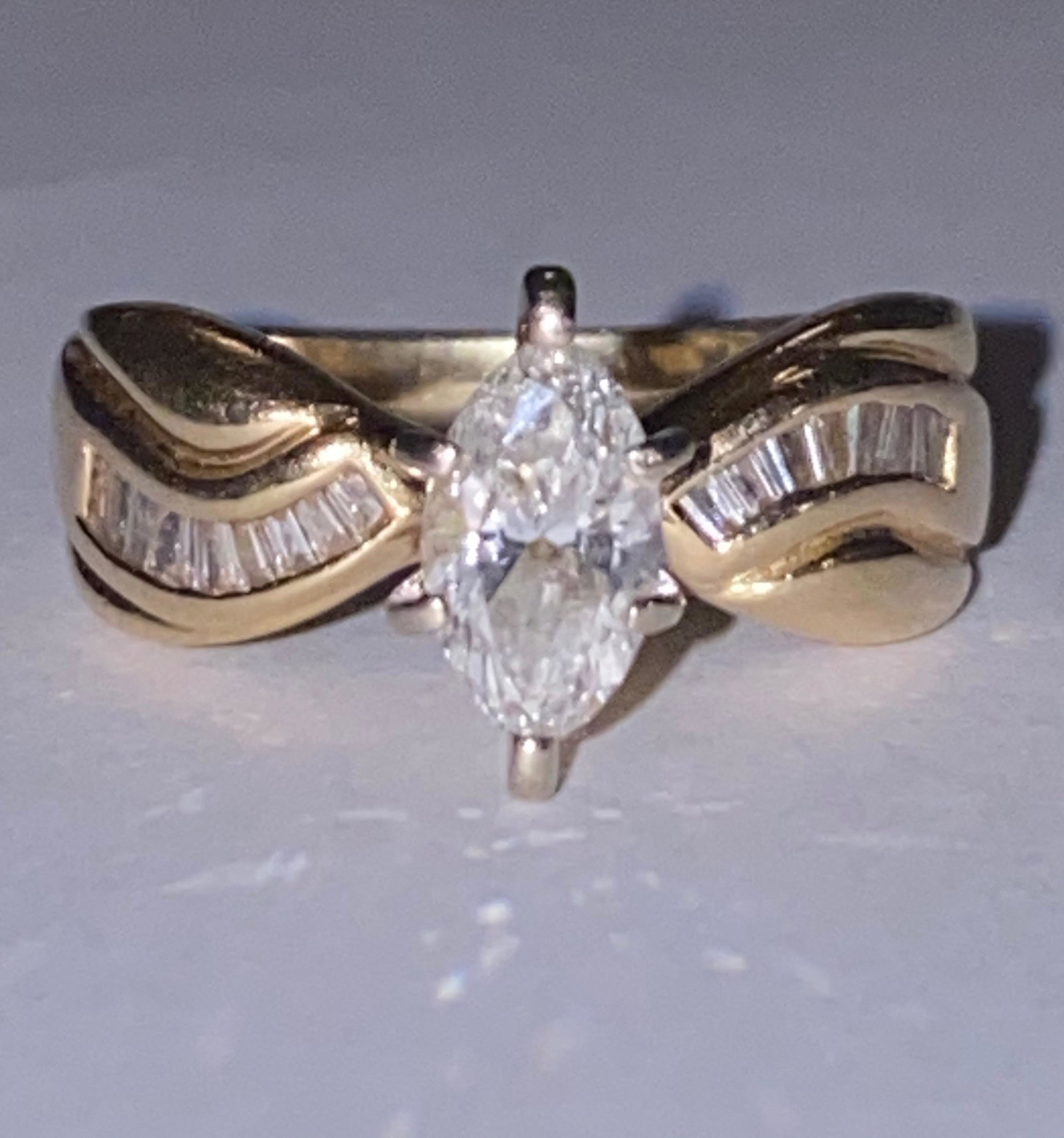 14K GOLD 0.50 CT SOLITAIRE SI, G DIAMOND RING: 14K GOLD 0.50 CT SOLITAIRE SI, G MARQUISE CUT DIAMOND RING. RING HAS A CENTER 0.50 CT MARQUISE CUT SOLITAIRE DIAMOND THAT IS SI IN CLARITY WITH A COLOR GRADING OF H-I, FLANKED WITH 0.20 TCW OF BAGUETT
