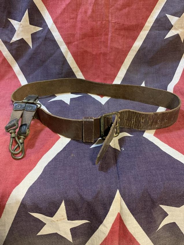CIVIL WAR CONFEDERATE BELT WITH SWORD HANGER: CIVIL WAR CONFEDERATE BELT WITH SWORD HANGER. BEAUTIFUL TARRED LEATHER BELT IN MINT SHAPE AND CONDITION WITH ATTACHED SWORD HINGES/HOOKS. A VERY RARE FIND AND AN EXCELLENT ADDITION TO YOUR COLLECTION.