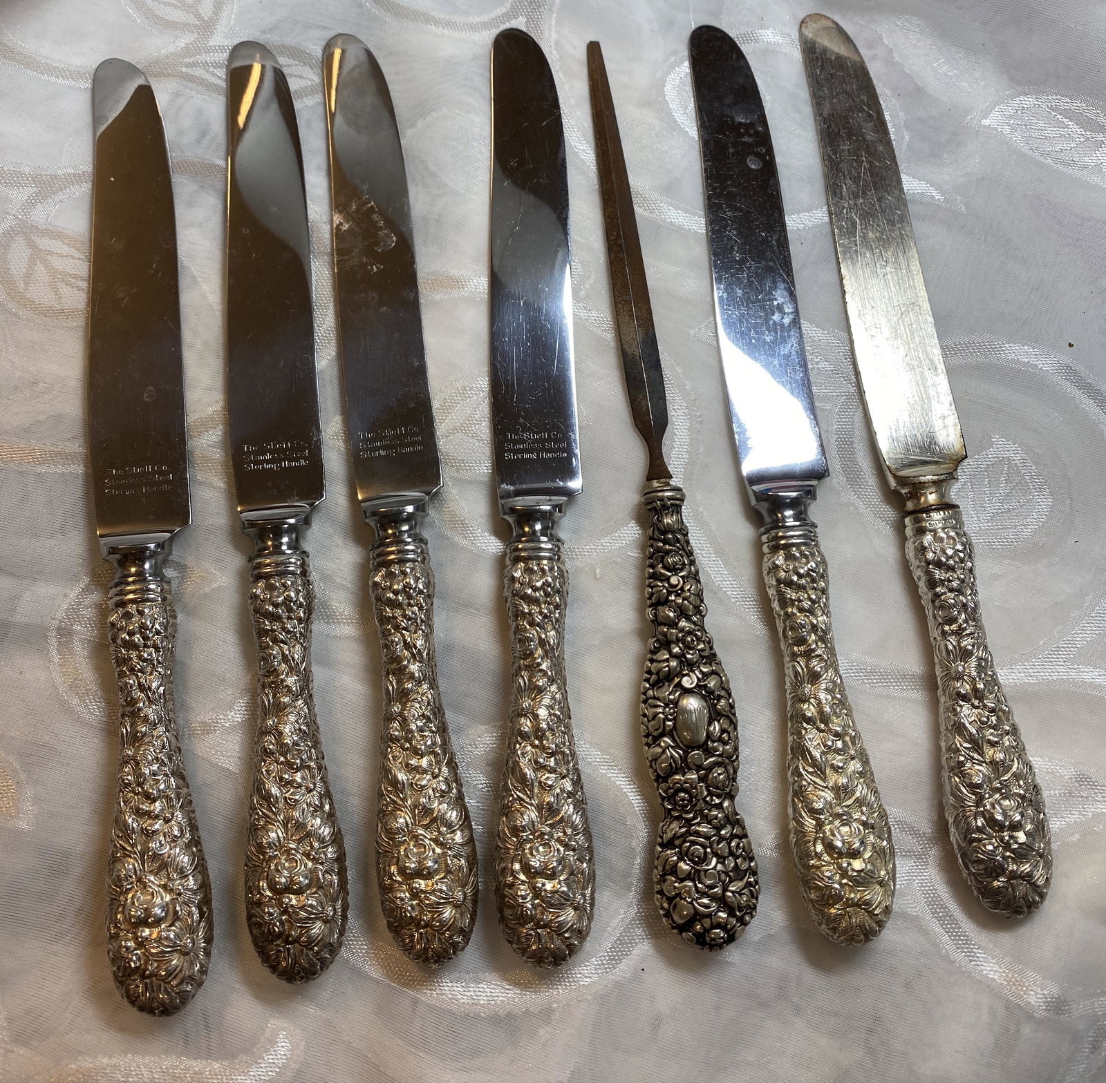 STEIFF LOT OF (6) STERLING SILVER BUTTER KNIVES & FILER: STEIFF LOT OF (6) STERLING SILVER BUTTER KNIVES & FILER. BEAUTIFUL BALTIMORE ROSE DESIGN HANDLES. PLEASE VIEW ALL DETAILED PICTURES. A GREAT FIND AND AN EXCELLENT ADDITION TO YOUR COLLECTION.