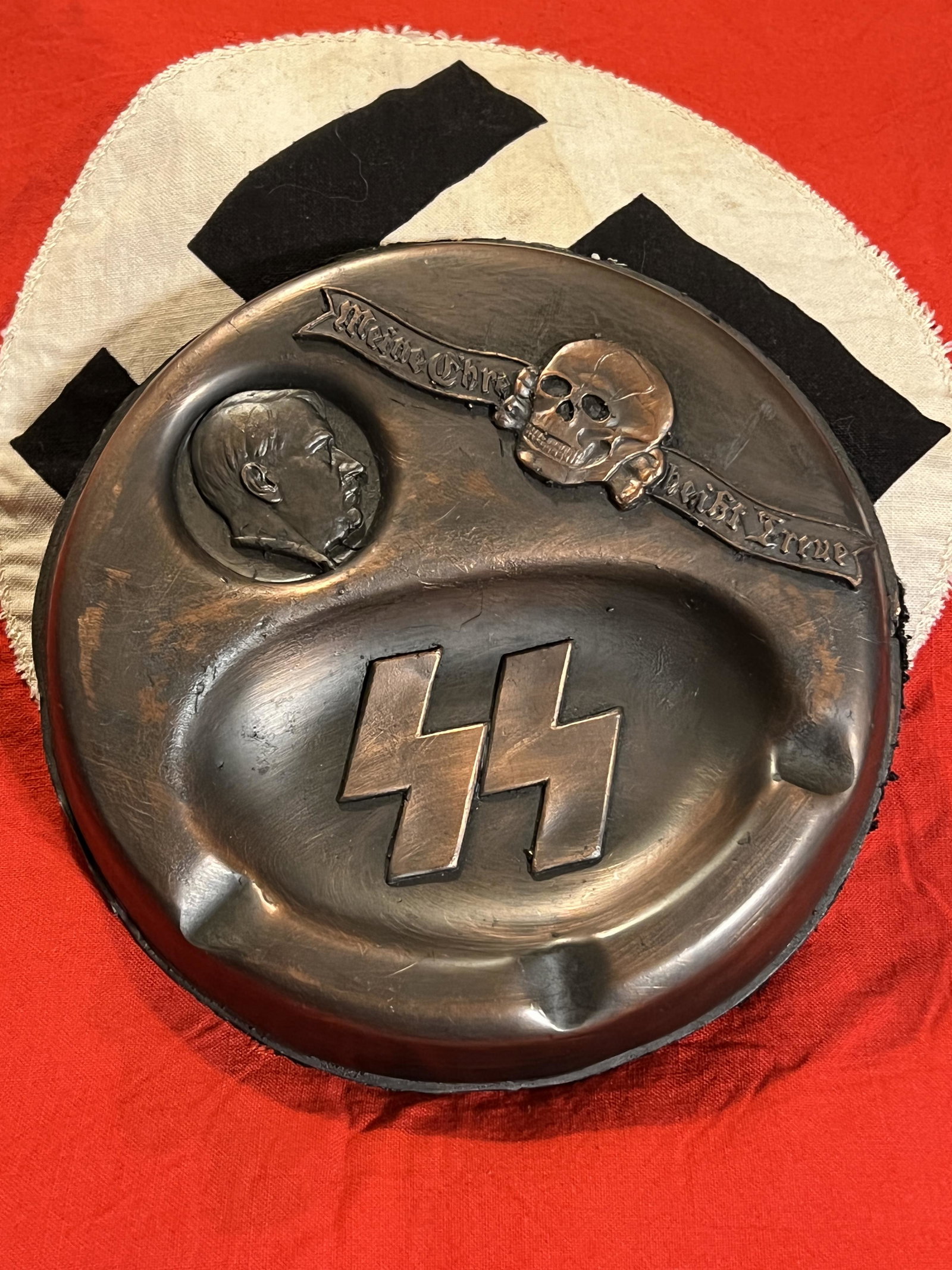 RARE WW2 GERMAN ADOLF HITLER SS OFFICER ASHTRAY: RARE WW2 GERMAN ADOLF HITLER SS OFFICER ASHTRAY. A VERY RARE FIND. THIS ASHTRAY DEPICTS ADOLF HITLER, THE SS INSIGNIA, AND THE SKULL INSIGINA. IN MINT OVERALL SHAPE AND CONDITION SHOWCASING A NEAT PAT
