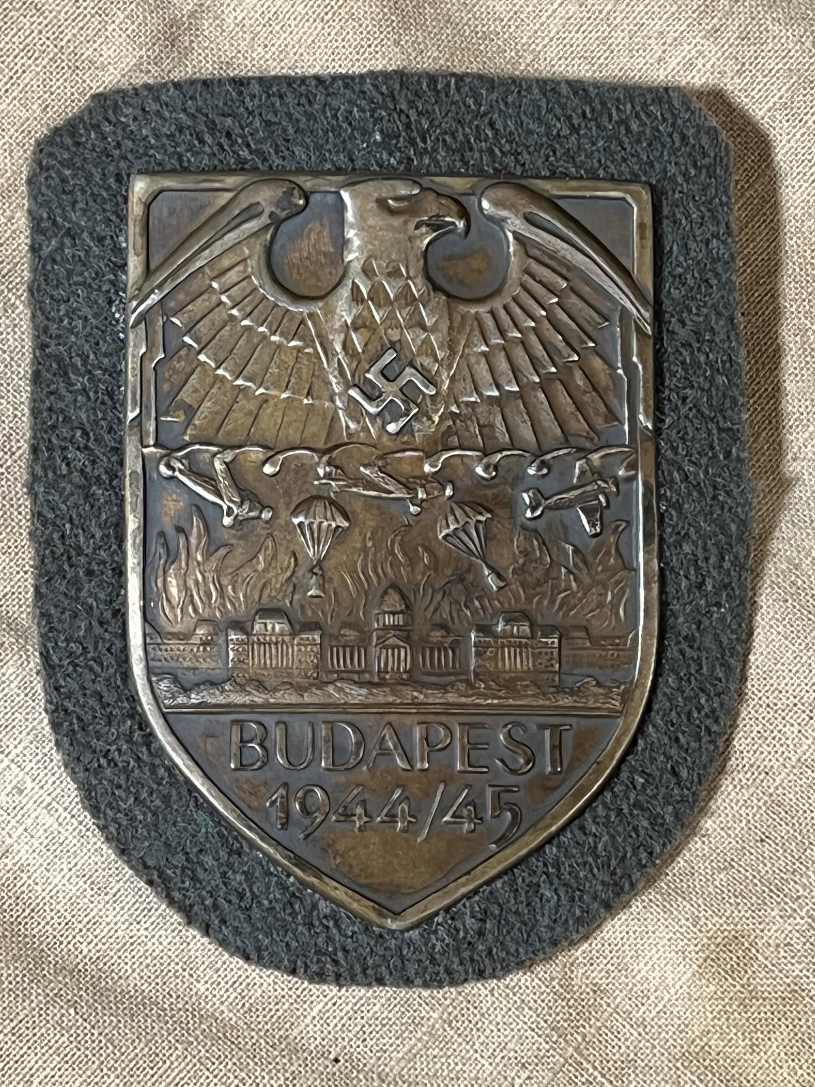 WW2 GERMAN NAZI BUDAPEST 1944/45 SHIELD SLEEVE BADGE: WW2 GERMAN NAZI BUDAPEST 1944/45 SHIELD SLEEVE BADGE. A RARE FIND. HAS THE MAKER MARKS ON THE BACK. APPEARS TO BE VERY WELL USED DURING BATTLE. A GREAT FIND AND AN EXCELLENT ADDITION TO YOUR COLLECTIO