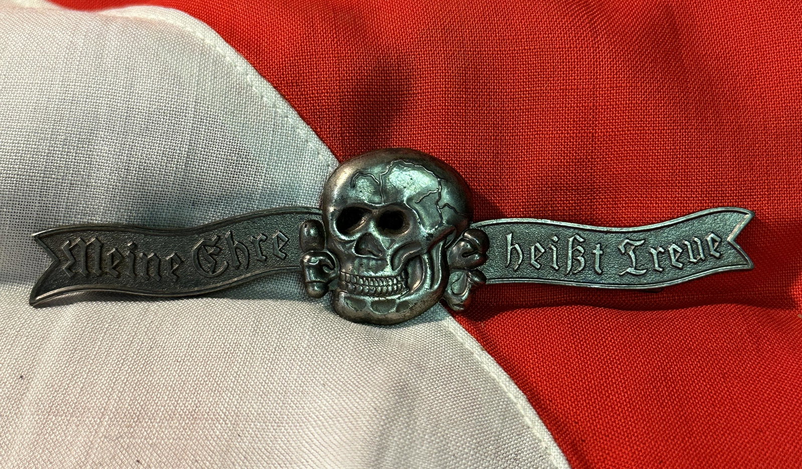 WW2 GERMAN TOTENKOPF SS SKULL CLASP BADGE - MEINE EHRE HEIBT TREUE: WW2 GERMAN TOTENKOPF SS SKULL CLASP BADGE - MEINE EHRE HEIBT TREUE. A RARE FIND. MAKER MARKED RZM M1/34 ON THE REAR. IT IS IN GOOD SHAPE AND CONDITION WITH A NICE PATINA THROUGHOUT. SHOWS WEAR AND TEA