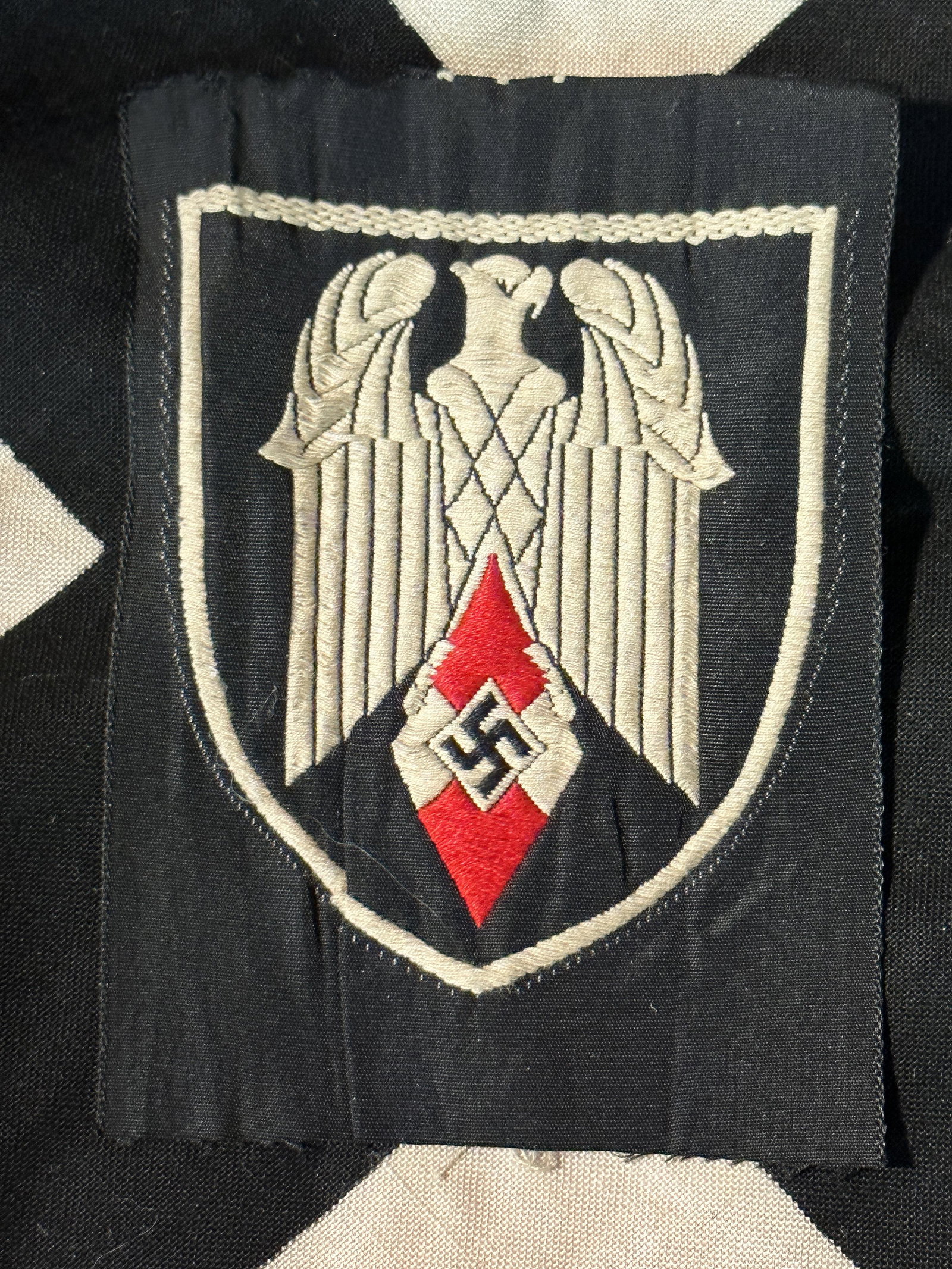 WW2 GERMAN HITLER YOUTH (HITLERJUGEND) FLAG BEARERS INSIGNIA: WW2 GERMAN HITLER YOUTH (HITLERJUGEND) FLAG BEARERS INSIGNIA. Cloth machine Bevo embroidered example. This badge showing an white eagle upon the HJ (Hitler Youth diamond on a black shield shaped backg