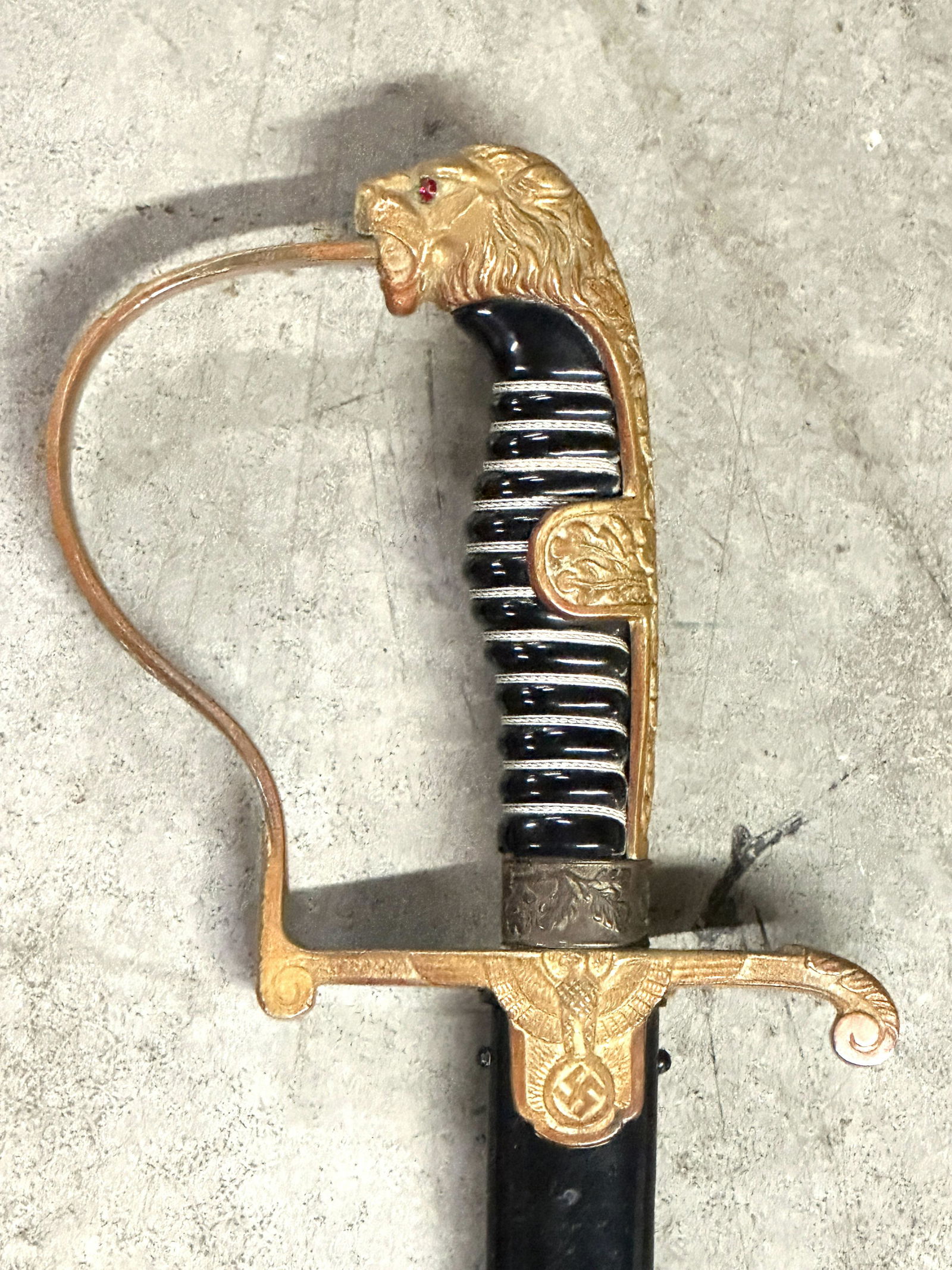 WW2 GERMAN LIONS HEAD WITH RUBY EYES SWORD WITH SHEATH - VET BRING BACK: WW2 GERMAN LIONS HEAD WITH RUBY EYES SWORD WITH SHEATH - VET BRING BACK. A VERY RARE FIND. GOLD WASHED ALLOY; GRIP GUARD AND POMMEL; THREE STRAND WIRE WRAPPED GRIP, INSET "RUBY" COLORED EYES IN LIONS