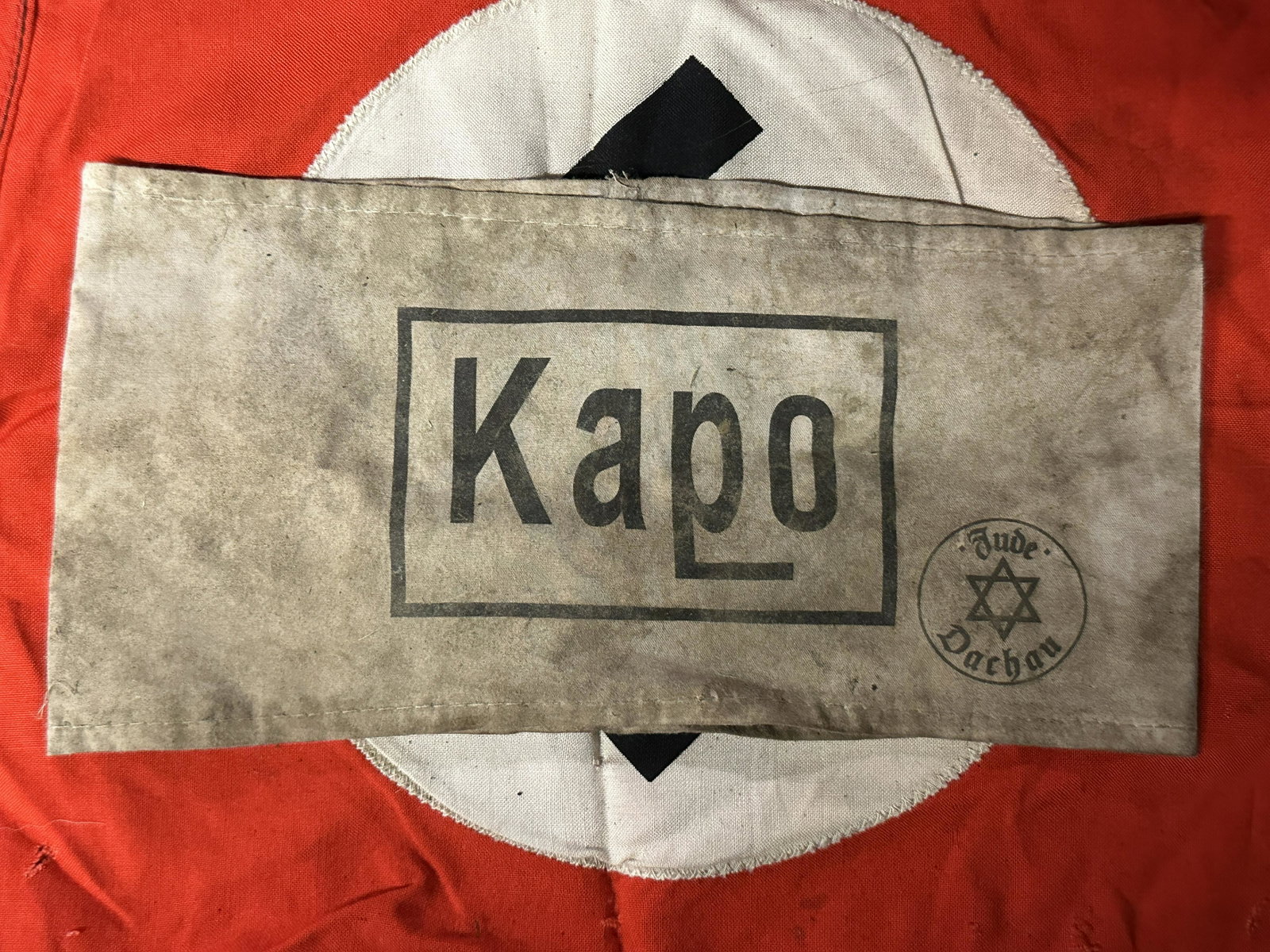 WW2 GERMAN KAPO ARMBAND WITH JUDE DACHAU INSPECTION STAMP: WW2 GERMAN KAPO ARMBAND WITH JUDE DACHAU INSPECTION STAMP. A RARE FIND. IT IS IN MINT OVERALL SHAPE AND CONDITION WITH A BEAUTIFUL OVERALL PATINA. SHOWS GOOD WEAR AND USE. PLEASE VIEW ALL DETAILED PIC