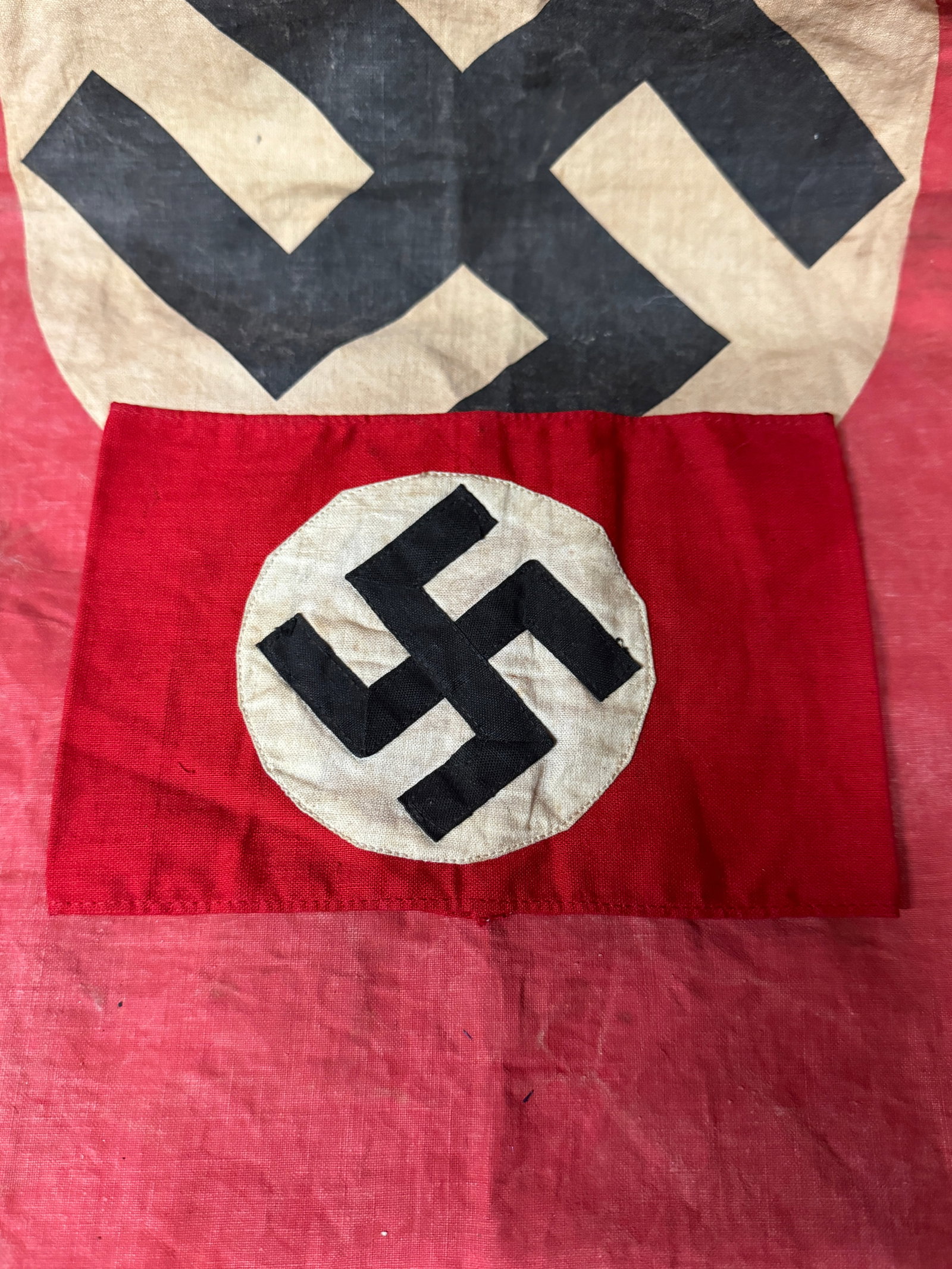 WW2 GERMAN NSDAP POLITICAL ARMBAND WITH RZM TAG: WW2 GERMAN NSDAP POLITICAL ARMBAND WITH RZM TAG. Armband is made of nice quality red cotton linen material with sewn white circle with sewn black swastika, with early type paper RZM tag on the inside.